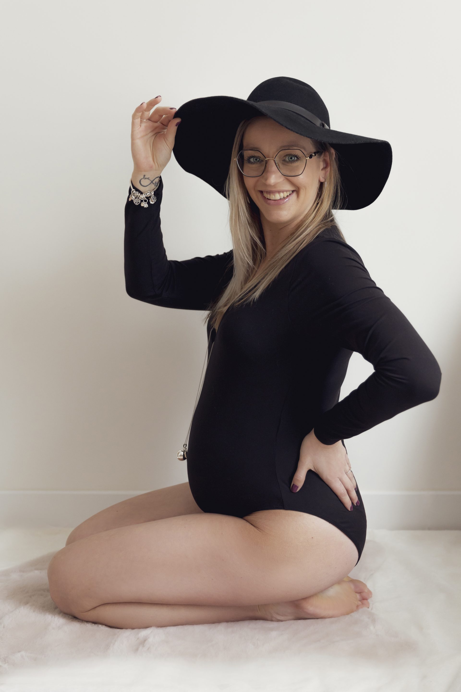 grossesse-nice photo de grossesse d'une femme agenouillée par terre, portant un body et un chapeau noir