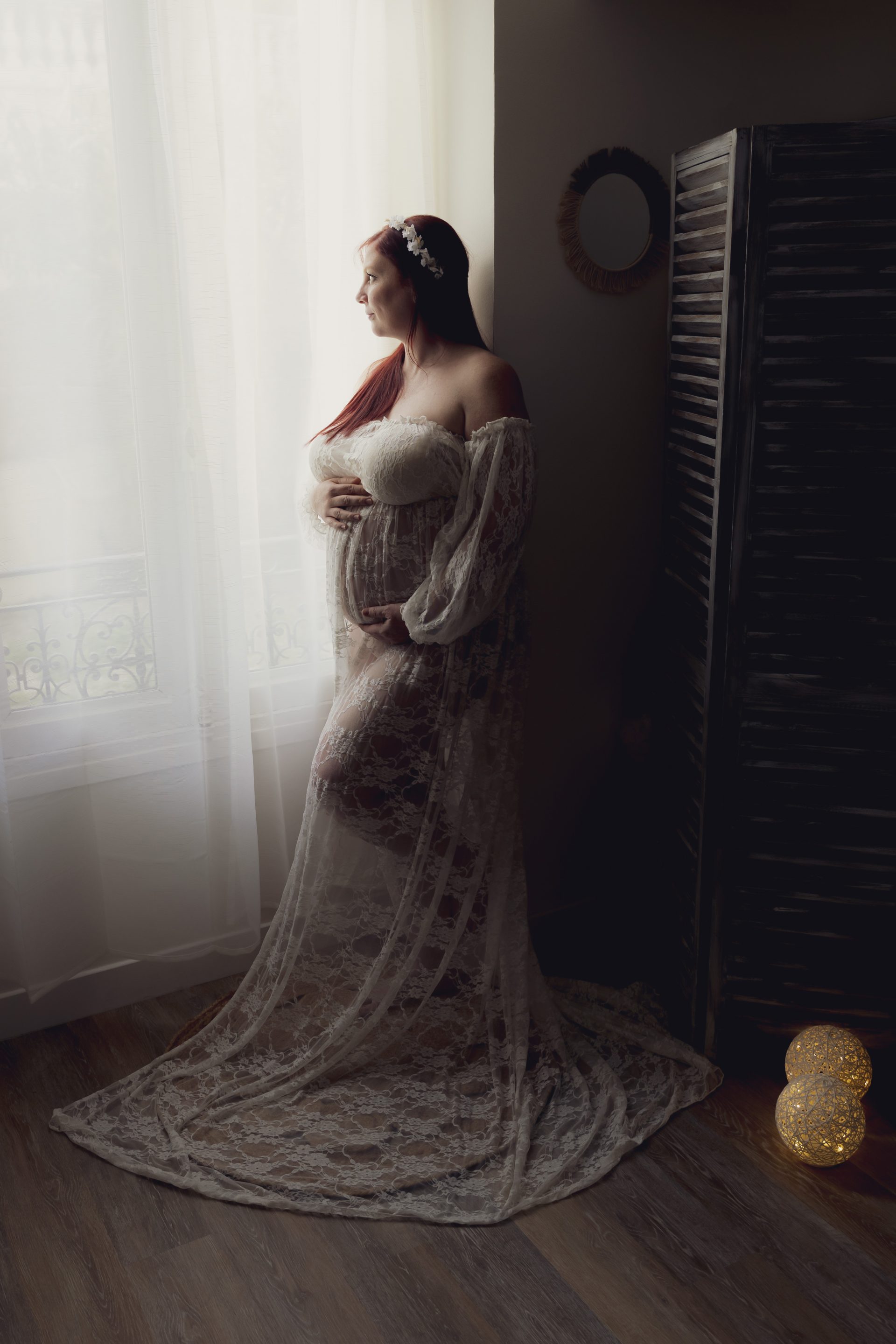 grossesse-studio-nice photo de grossesse d'une maman qui regarde par la fenêtre en touchant son ventre