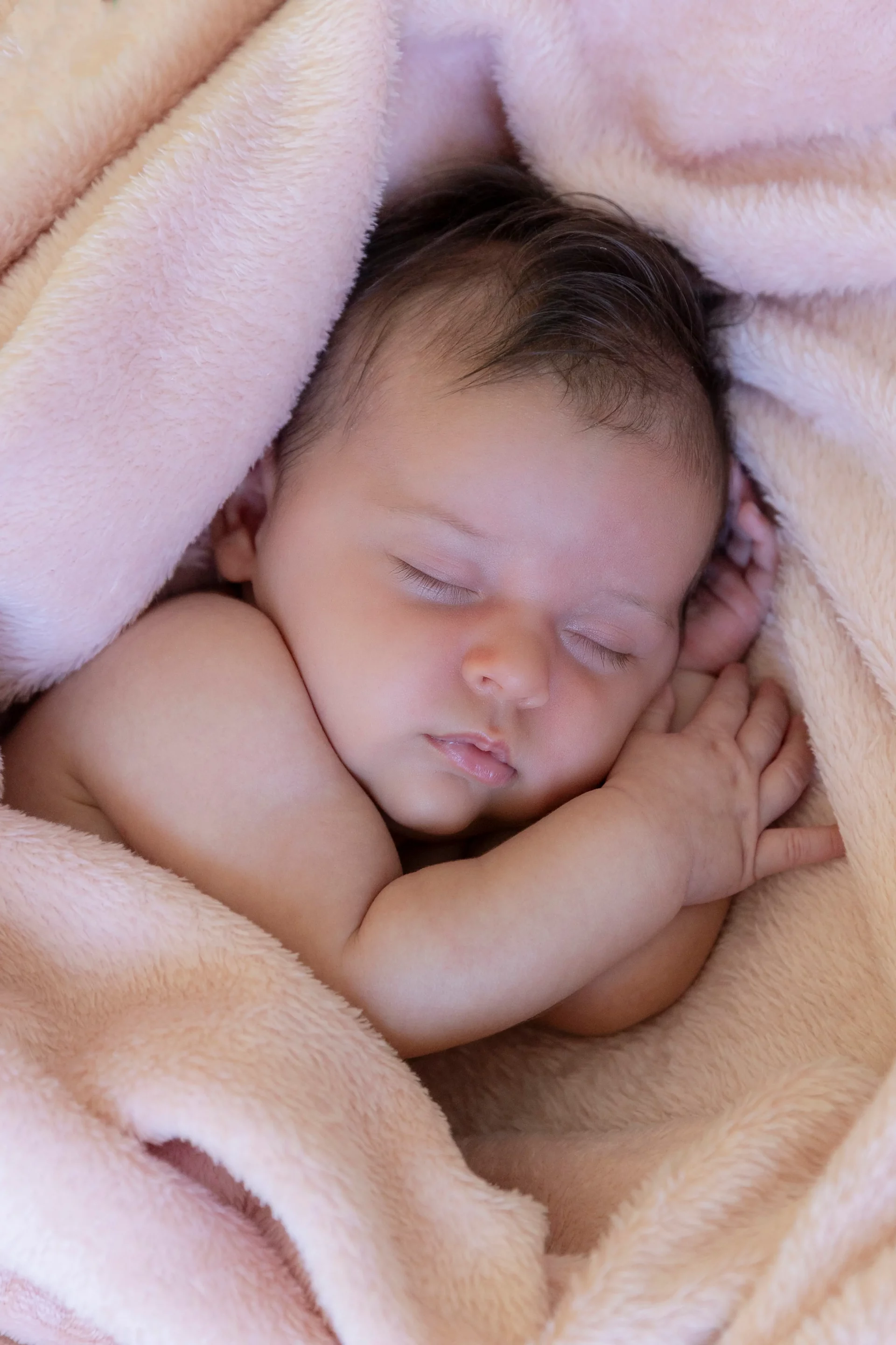 photo naissance d'un bébé endormi enveloppé dans une couverture rose