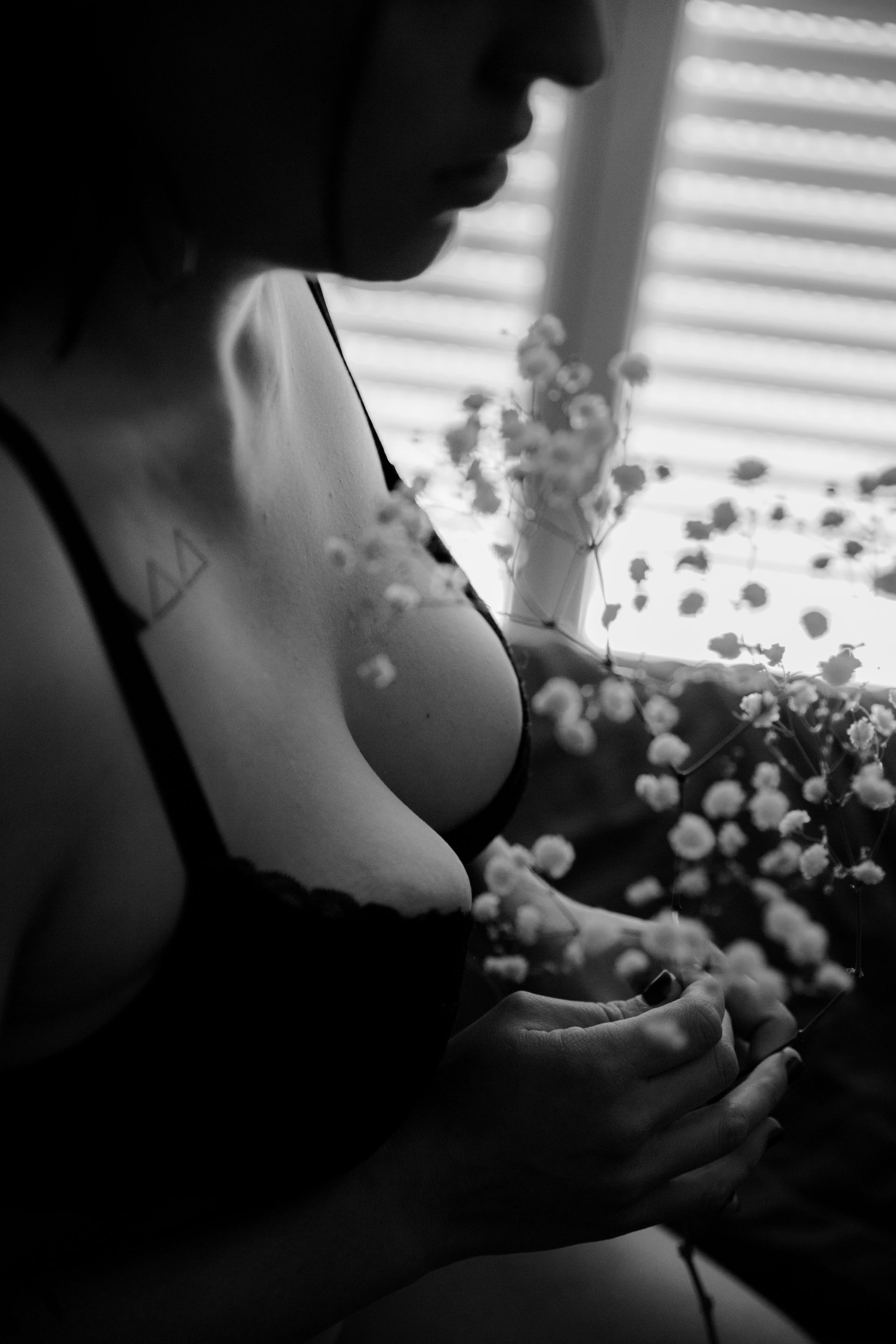 photo boudoir en noir et blanc, en gros plan sur la poitrine avec des fleurs blanches