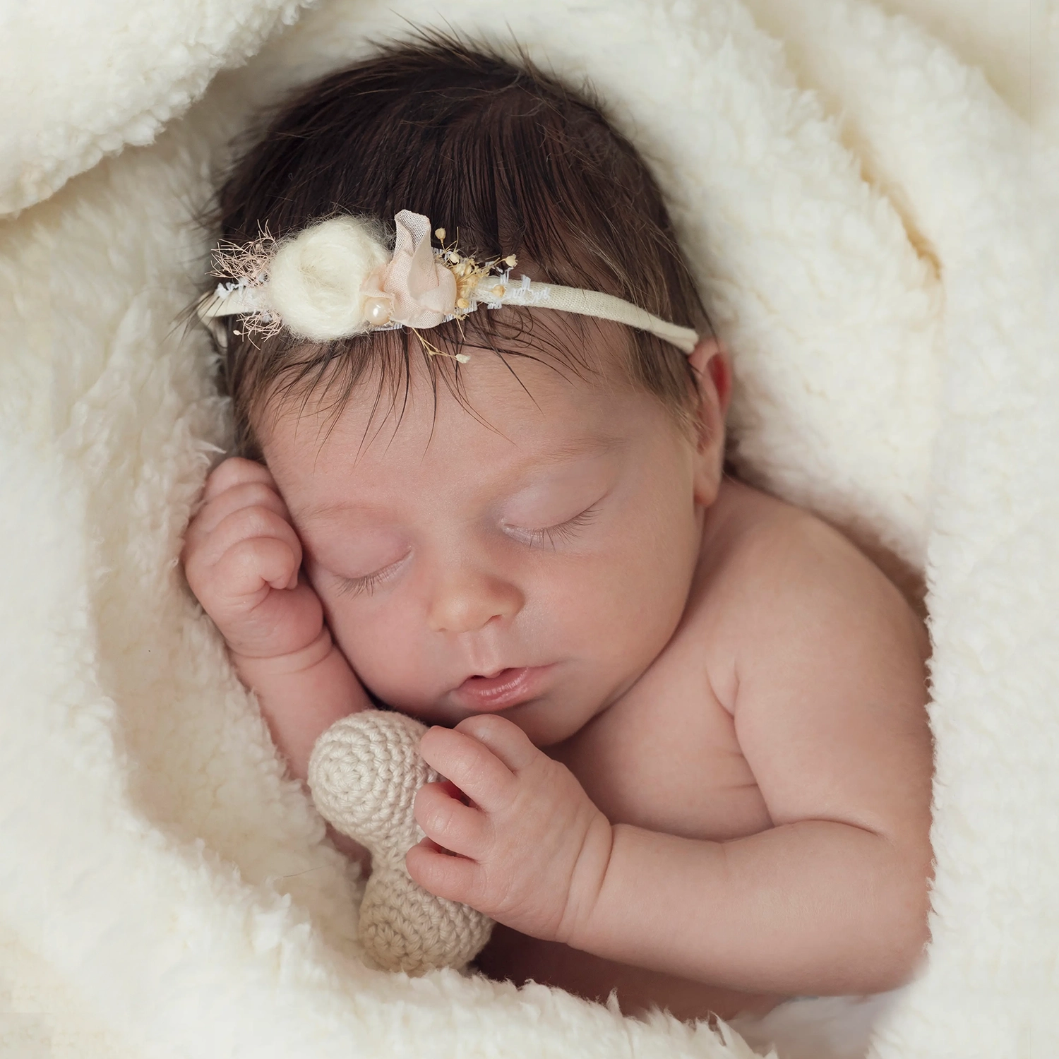 photo de naissance d'un bébé dans une couverture blanche,tenant une cœur beige