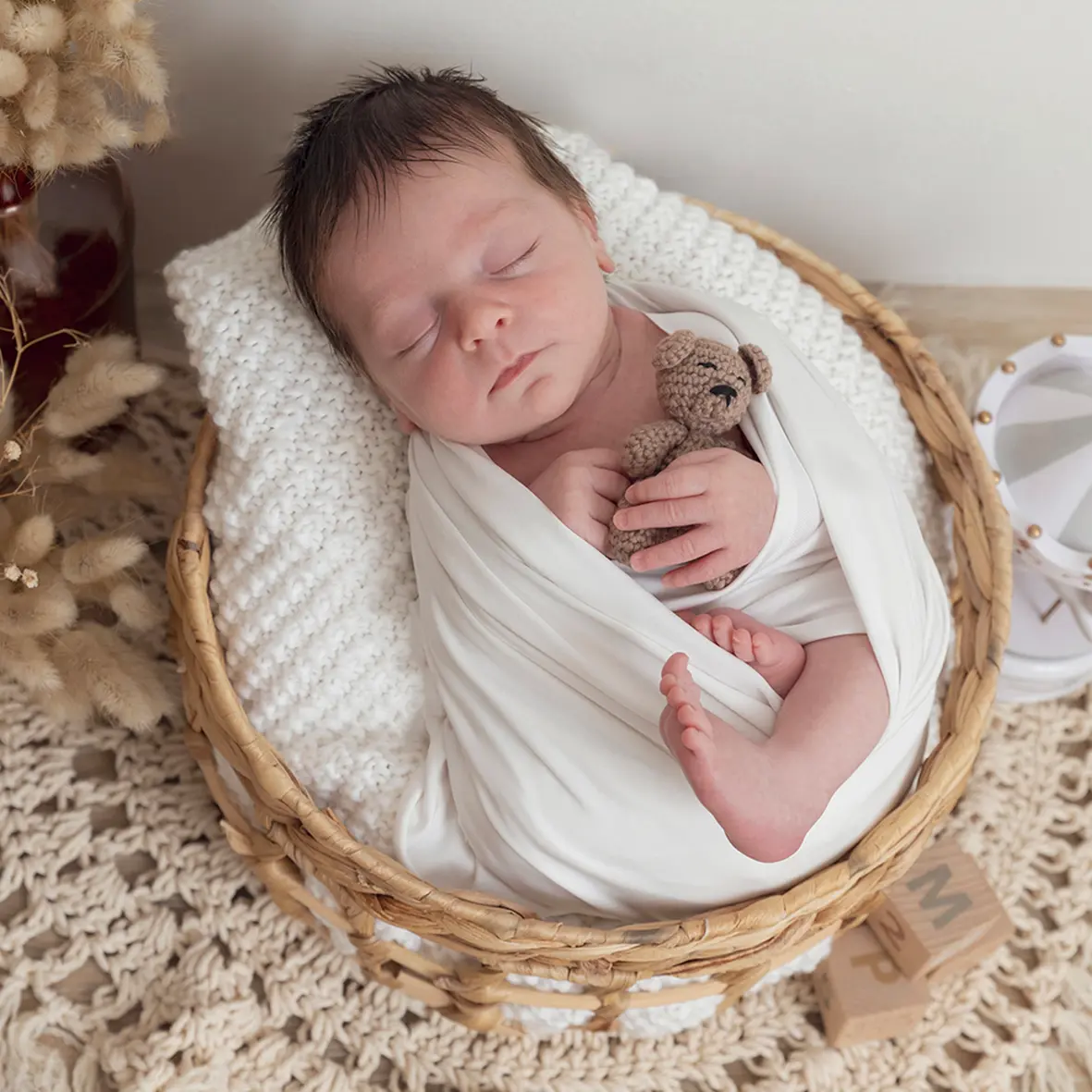 photo de naissance d'un bébé dans un panier, tenant un ourson