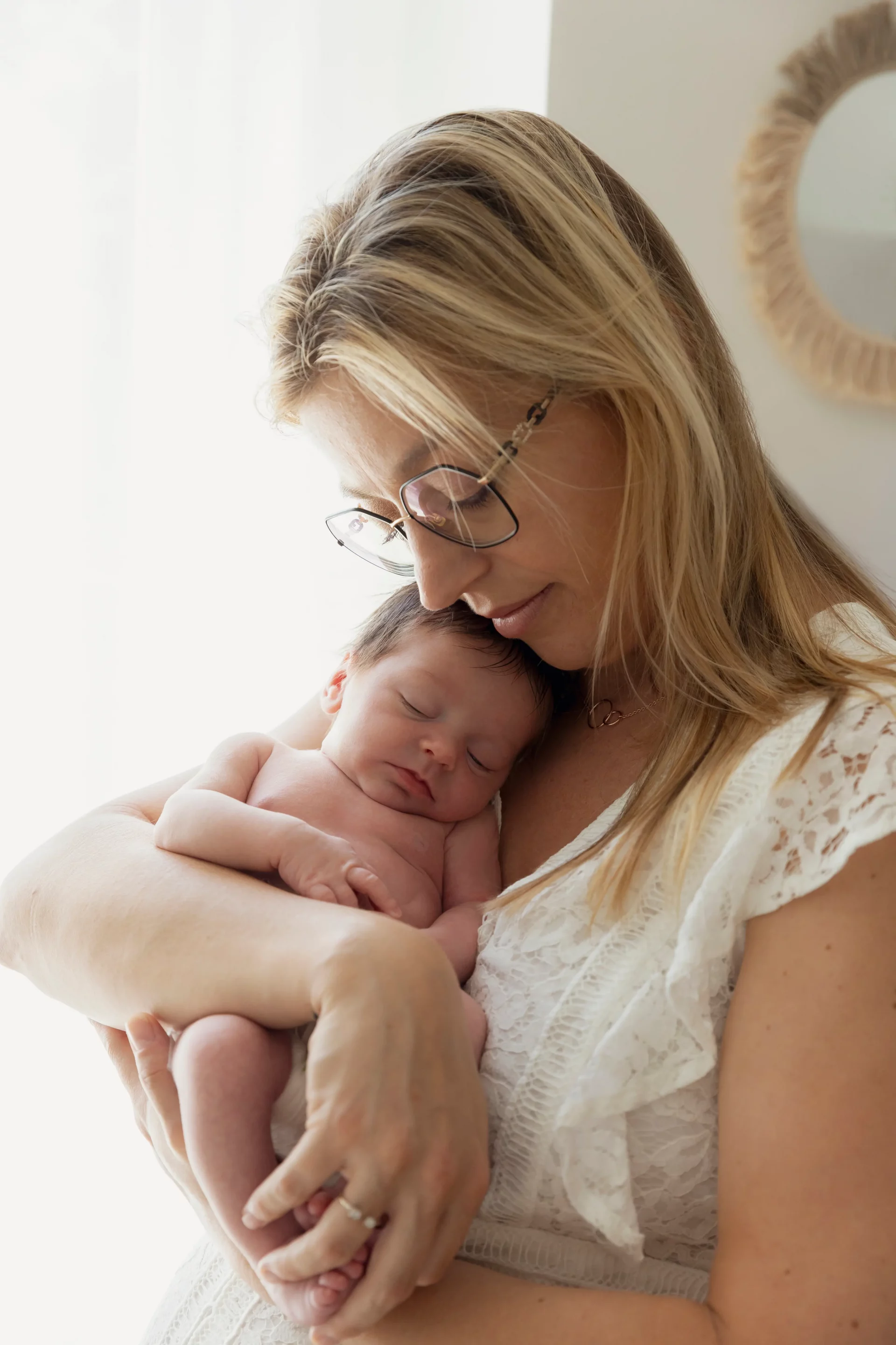 photo de naissance d'une maman portant son bébé et qui pose sa joue contre elle