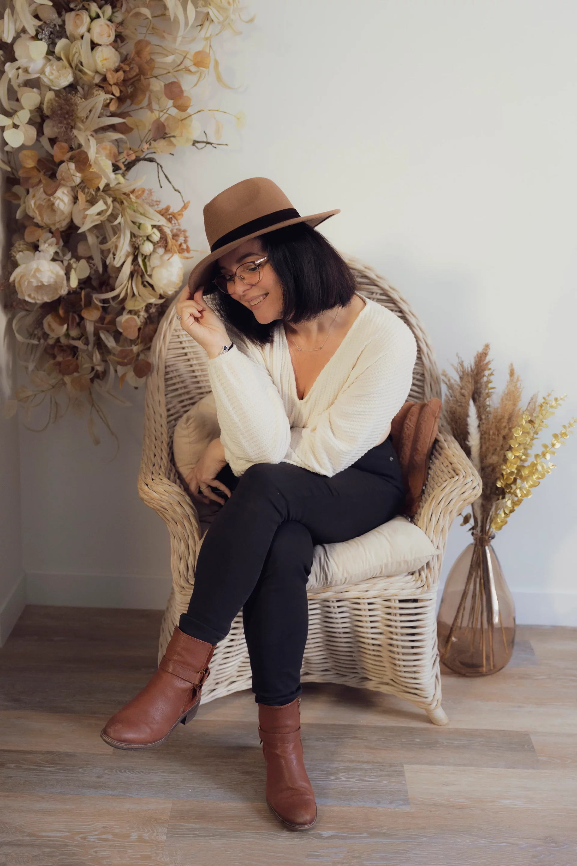 photo de sandra alvoet assise dans un fauteuil en osier, tenant un chapeau