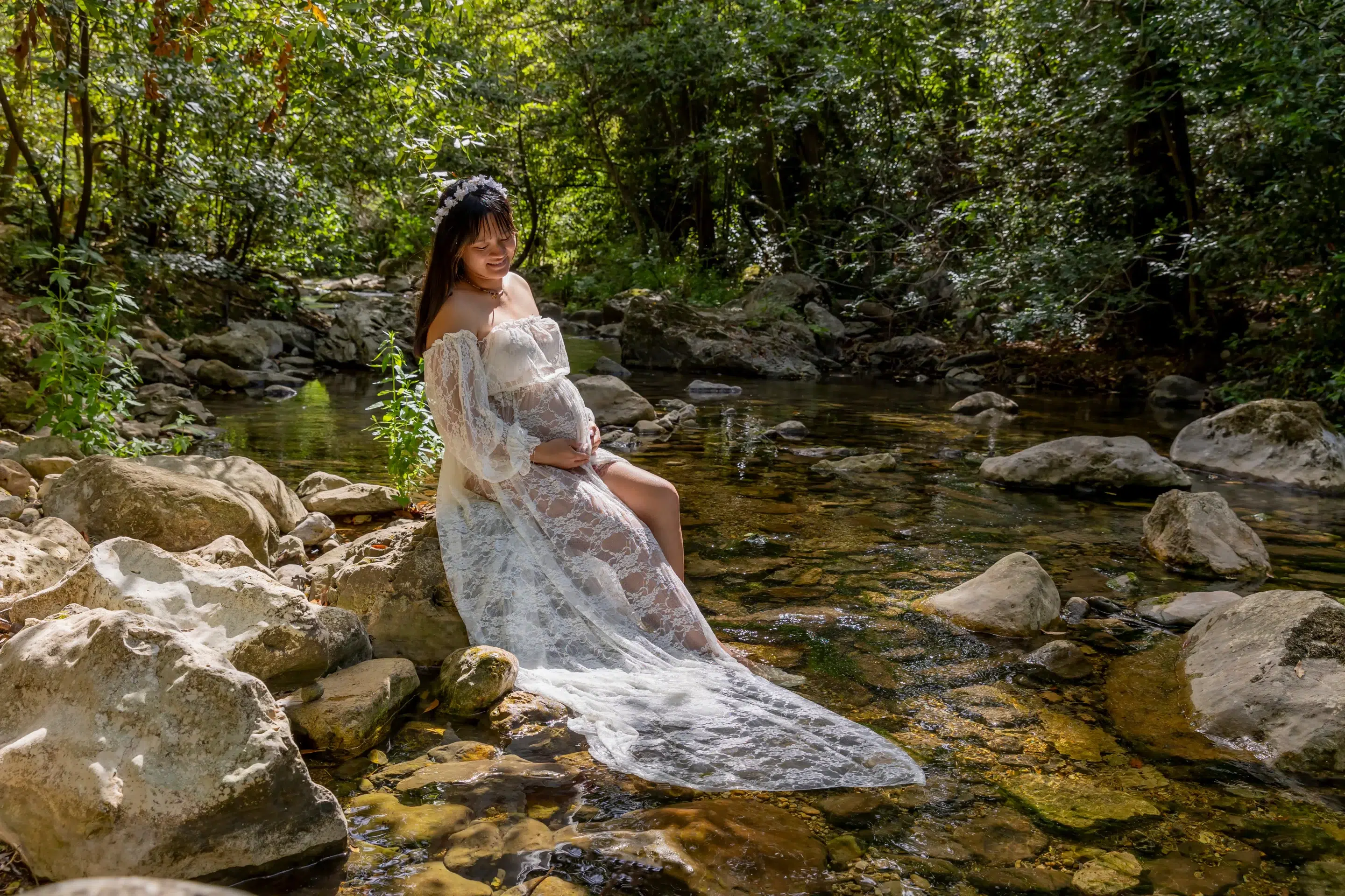 photo de grossesse en rivière d'une femme assise sur un rocher