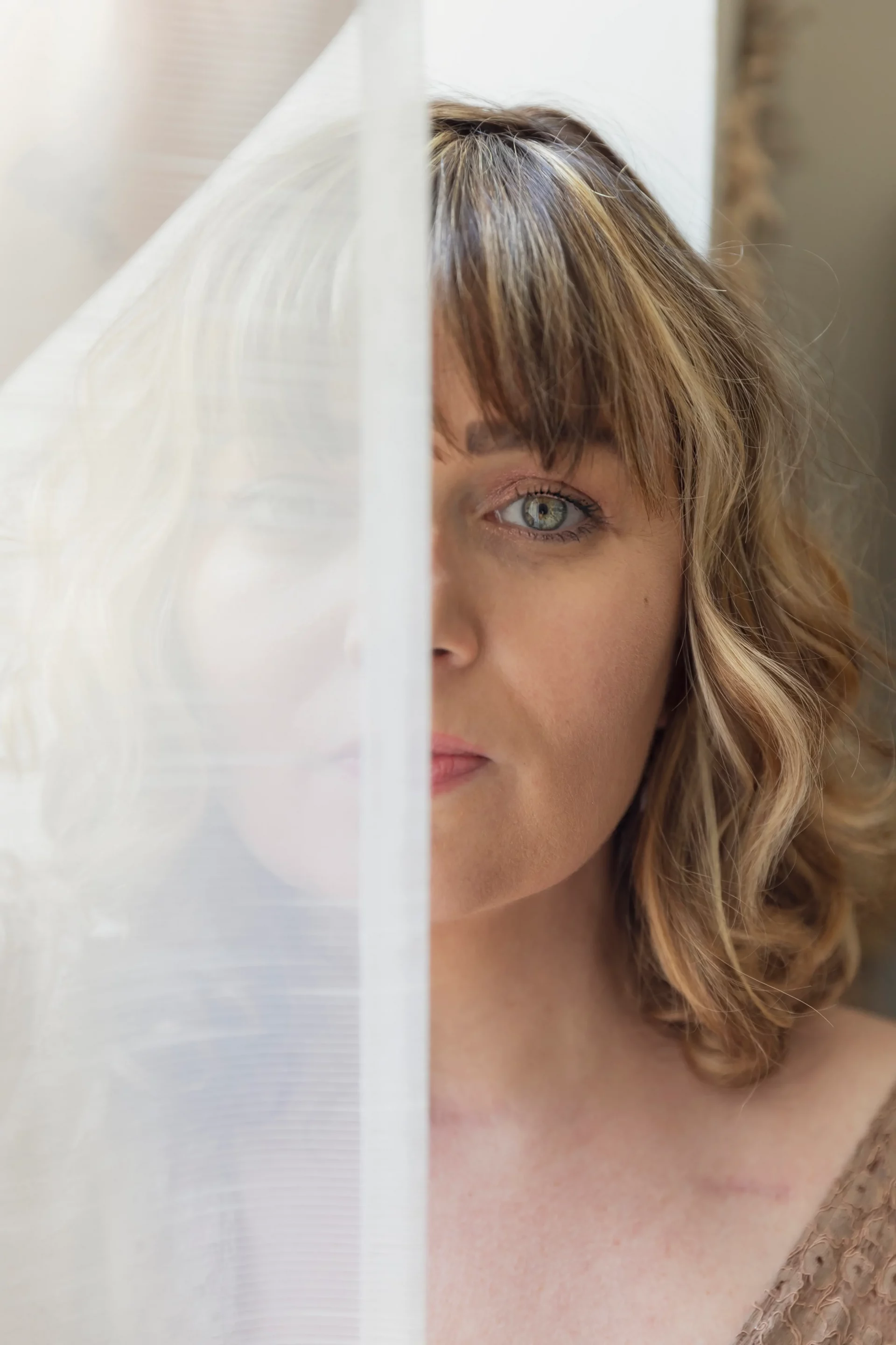 photgraphie-boudoir-femme-nice photographie boudoir d'une moitié de visage d'une femme, coupée en deux par un rideau blanc sandra-alvoet-photographe