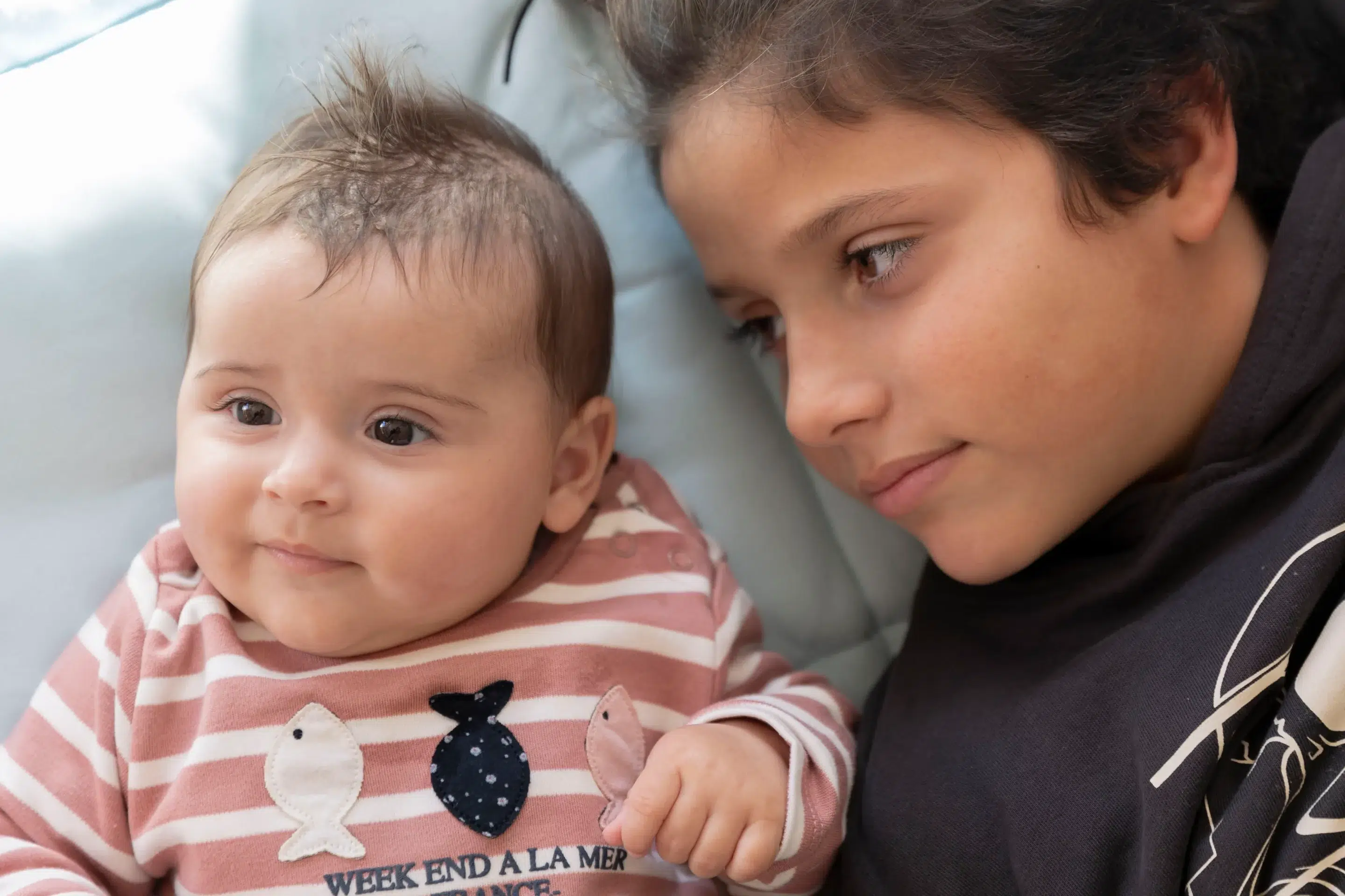 photographie d'une petite fille de 6 mois allongée sur une couverture et de son grand frère à côté d'elle qui la regarde sandra-alvoet-photographe