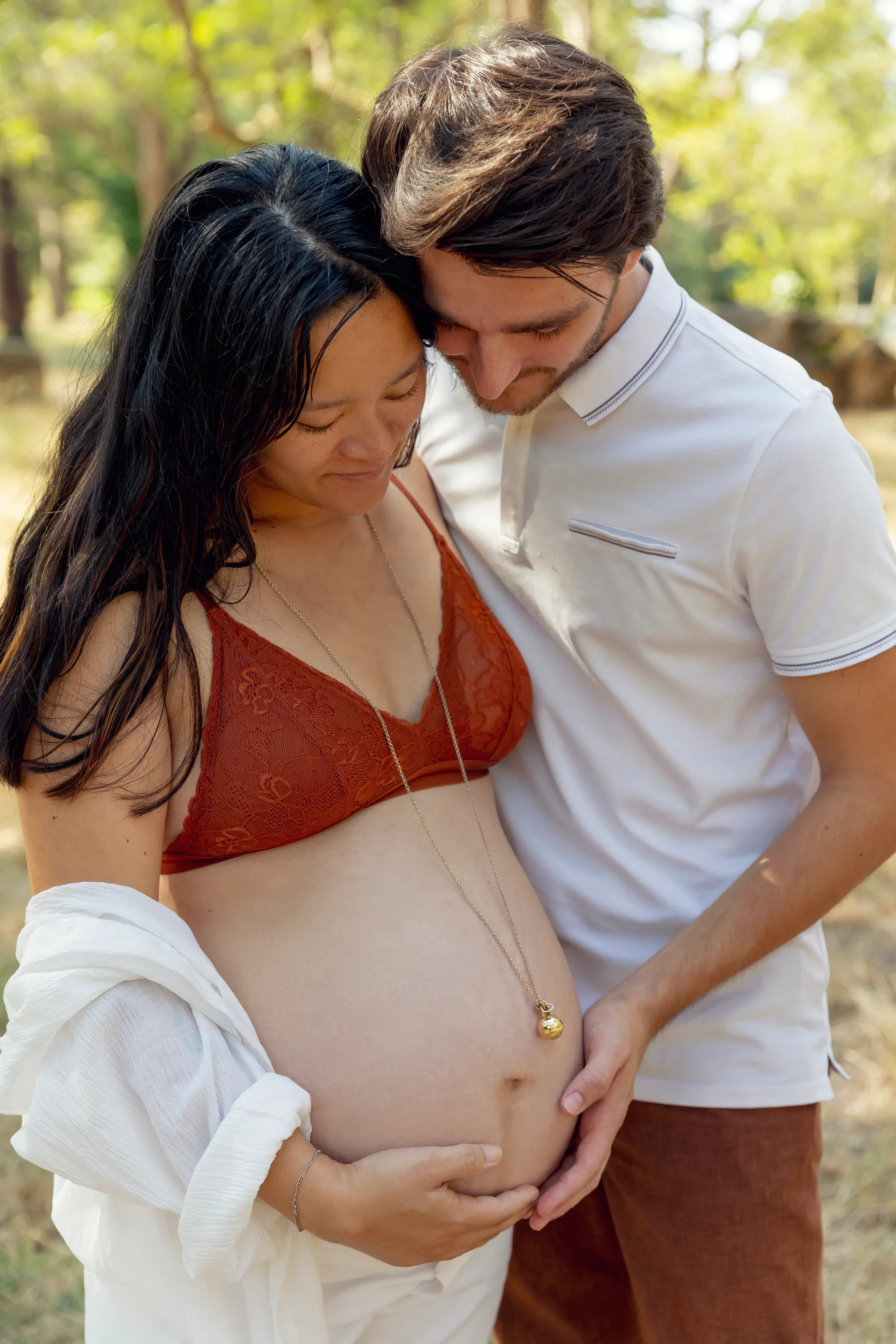photo-future-maman-exterieur photo d'un couple de futurs parents dans un parc à Nice, tenant et regardant le ventre sandra-alvoet-photographe