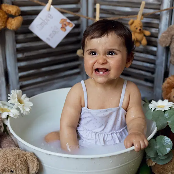 photo d'une petite fille de 9 mois dans un bain de lait souriant et montrant ses deux dents sandra-alvoet-photographe