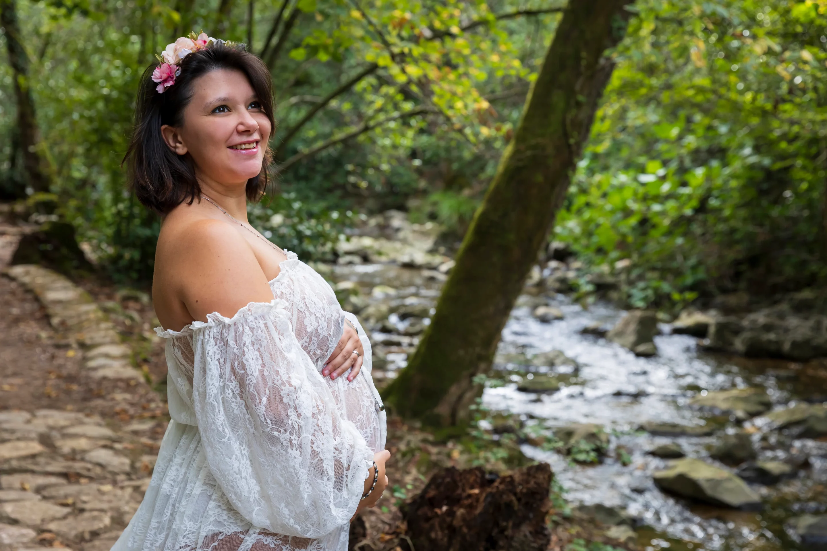 photo d'une femme enceinte, habillée d'une robe blanche en dentelle au bord d'une rivière à biot sandra-alvoet-photographe