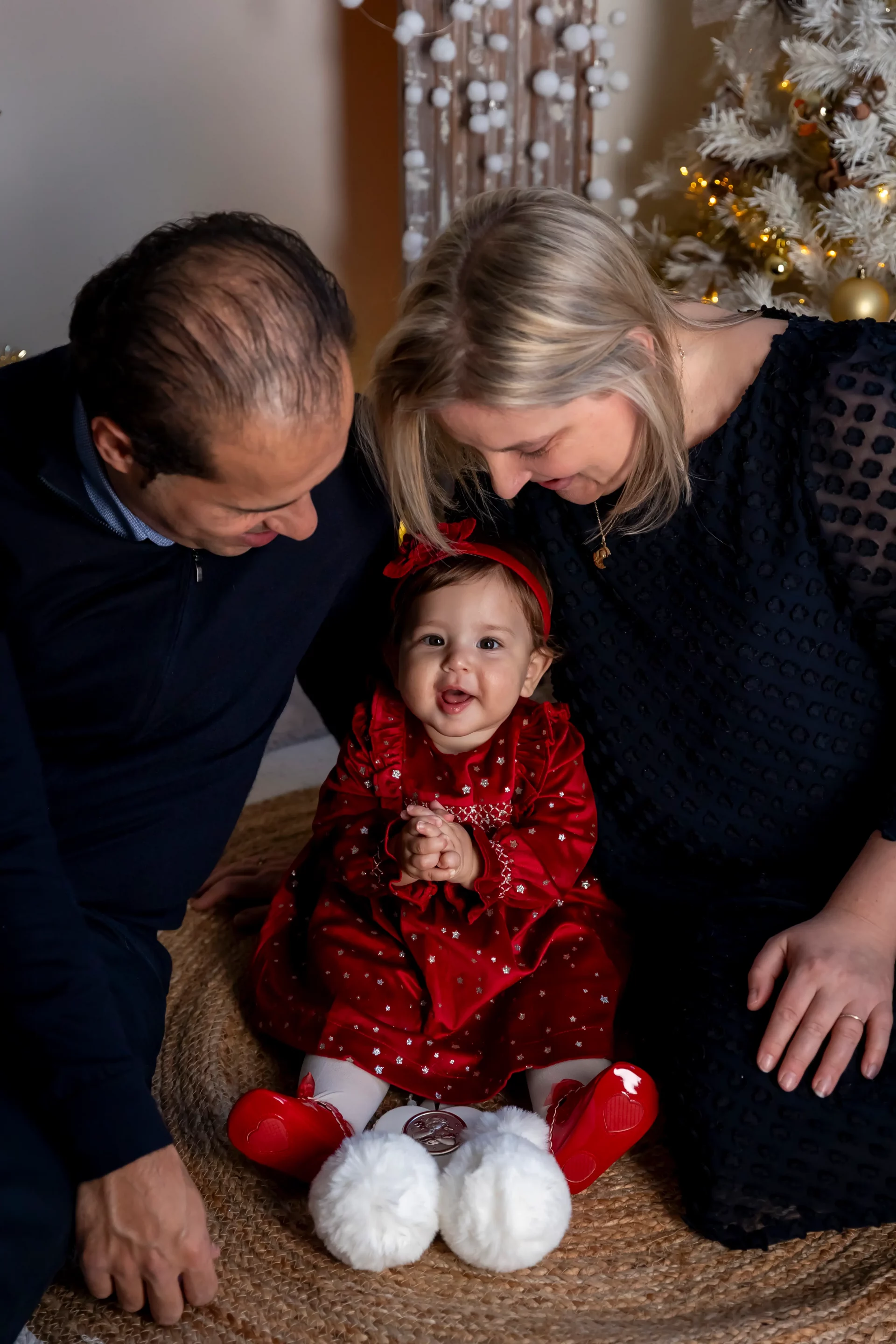 bebe-photo-famille photo de famille de Noël d'un couple qui regarde son bébé, tous les 3 assis par terre