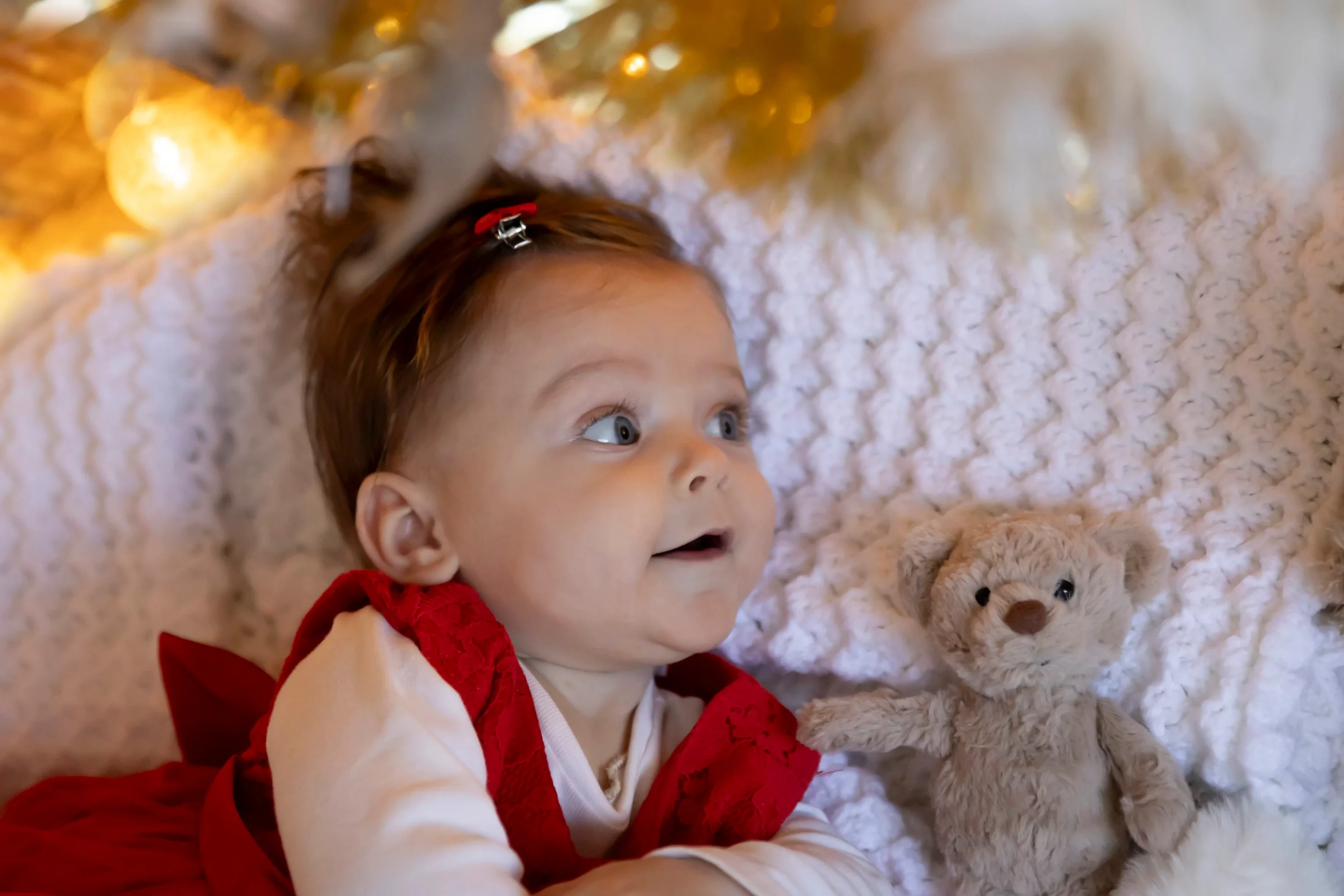 bebe-photo-noel-nice photo d'une bébé allongé sous un sapin et s'émerveillant des lumières de noël