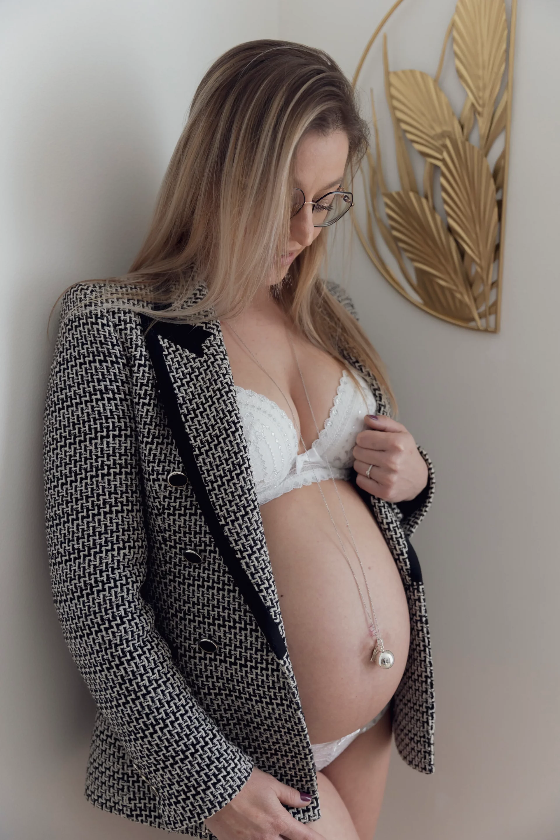 photo de grossesse d'une femme habillée en veste, regardant tendrement son ventre