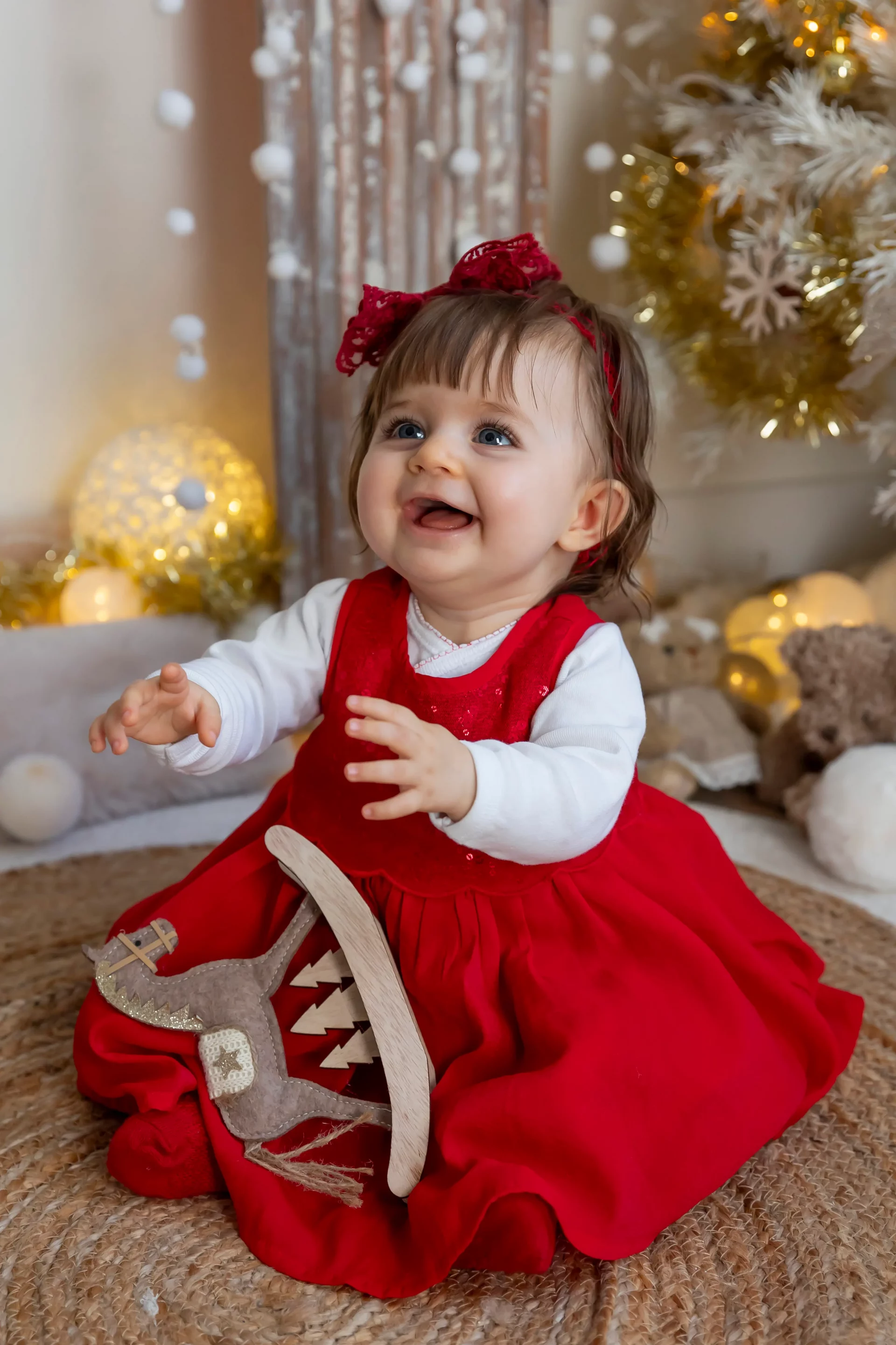 noel-photo-bebe photo de noël d'une petite fille en robe rouge, qui rit aux éclats