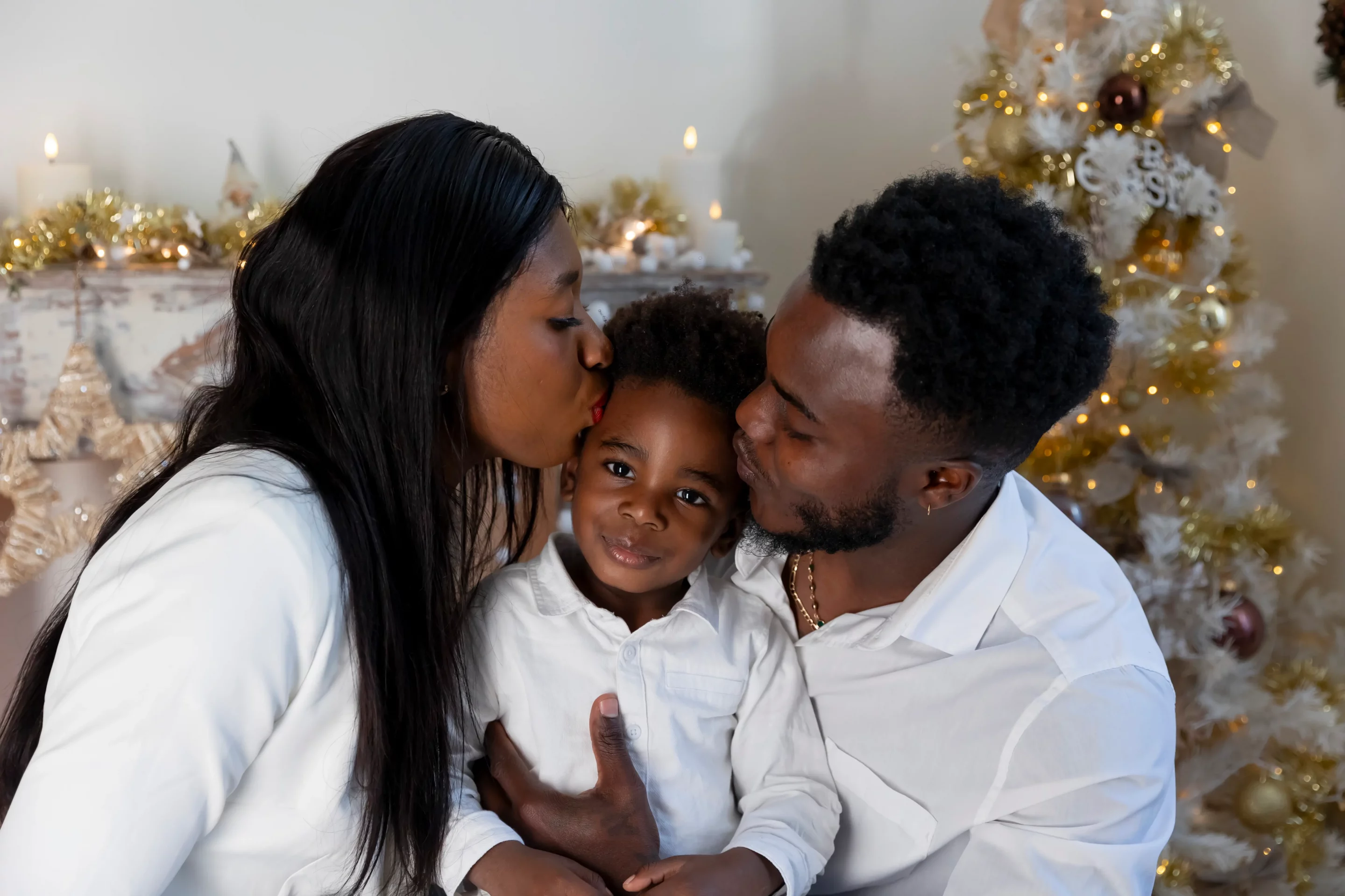 photo-de-famille-studio-paca photo de noël de deux parents qui embrassent leur fils sur les joues