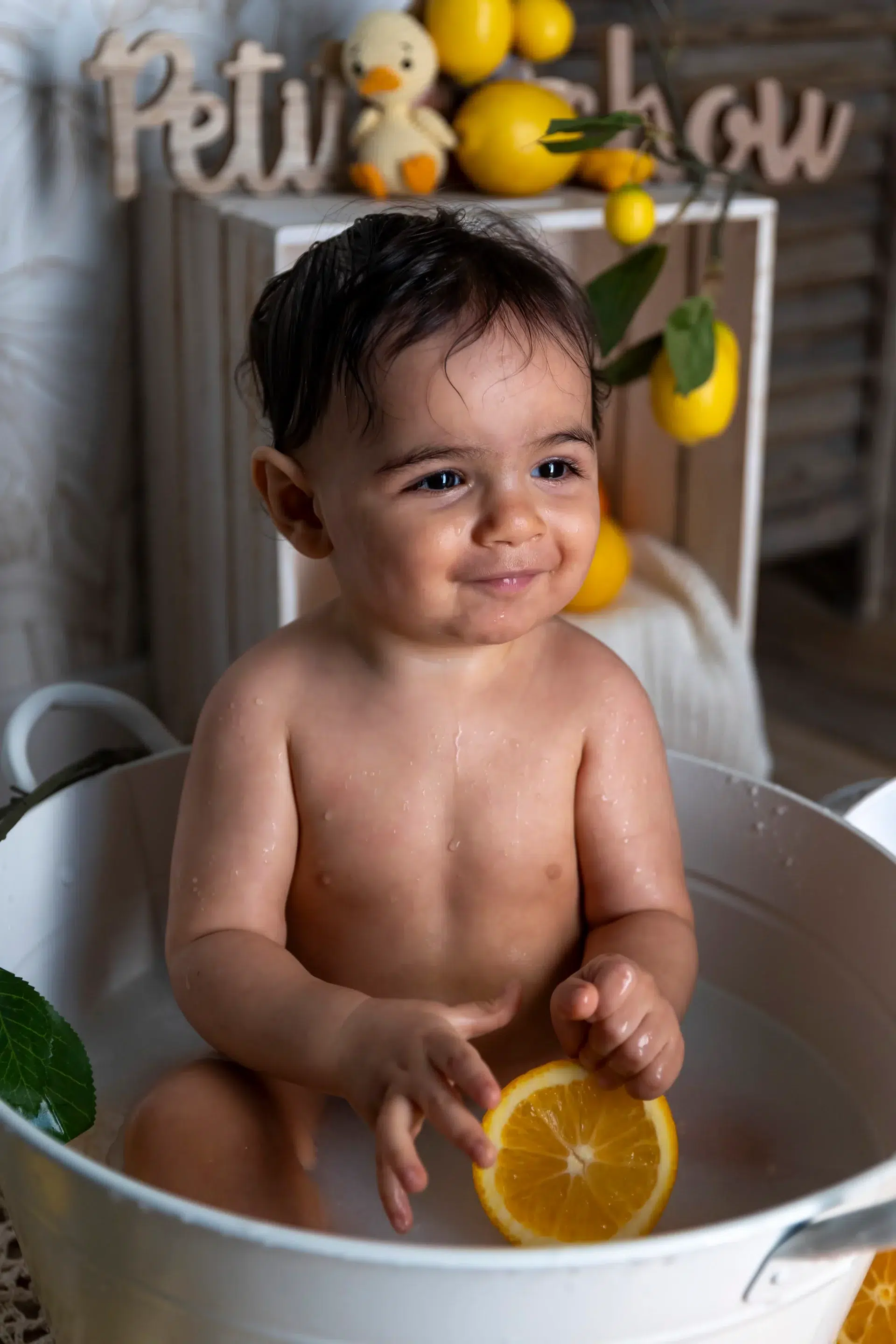 photo bain de lait d'un petit garçon souriant tenant une orange