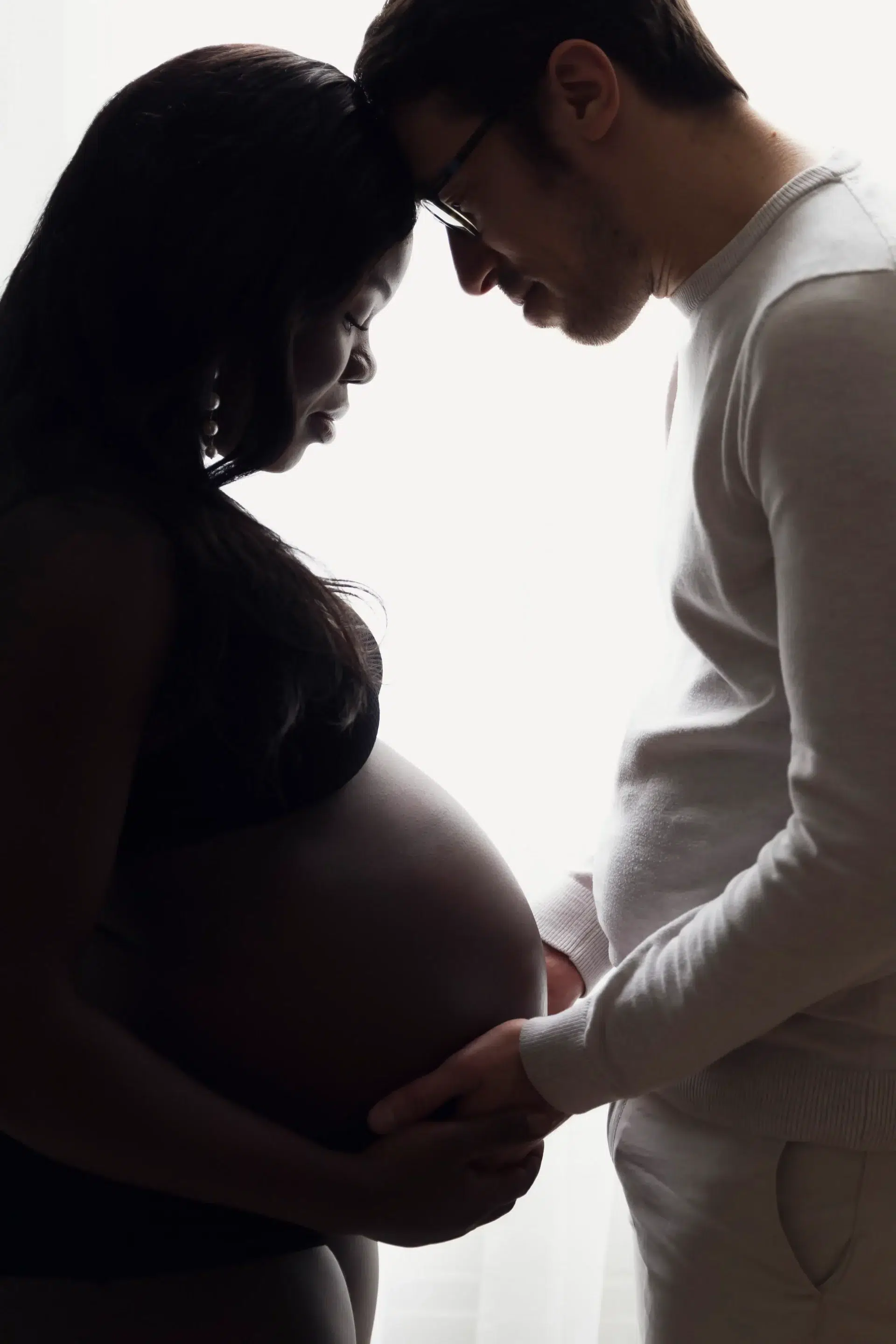 photo de grossesse, d'un couple front contre front et regardant le ventre