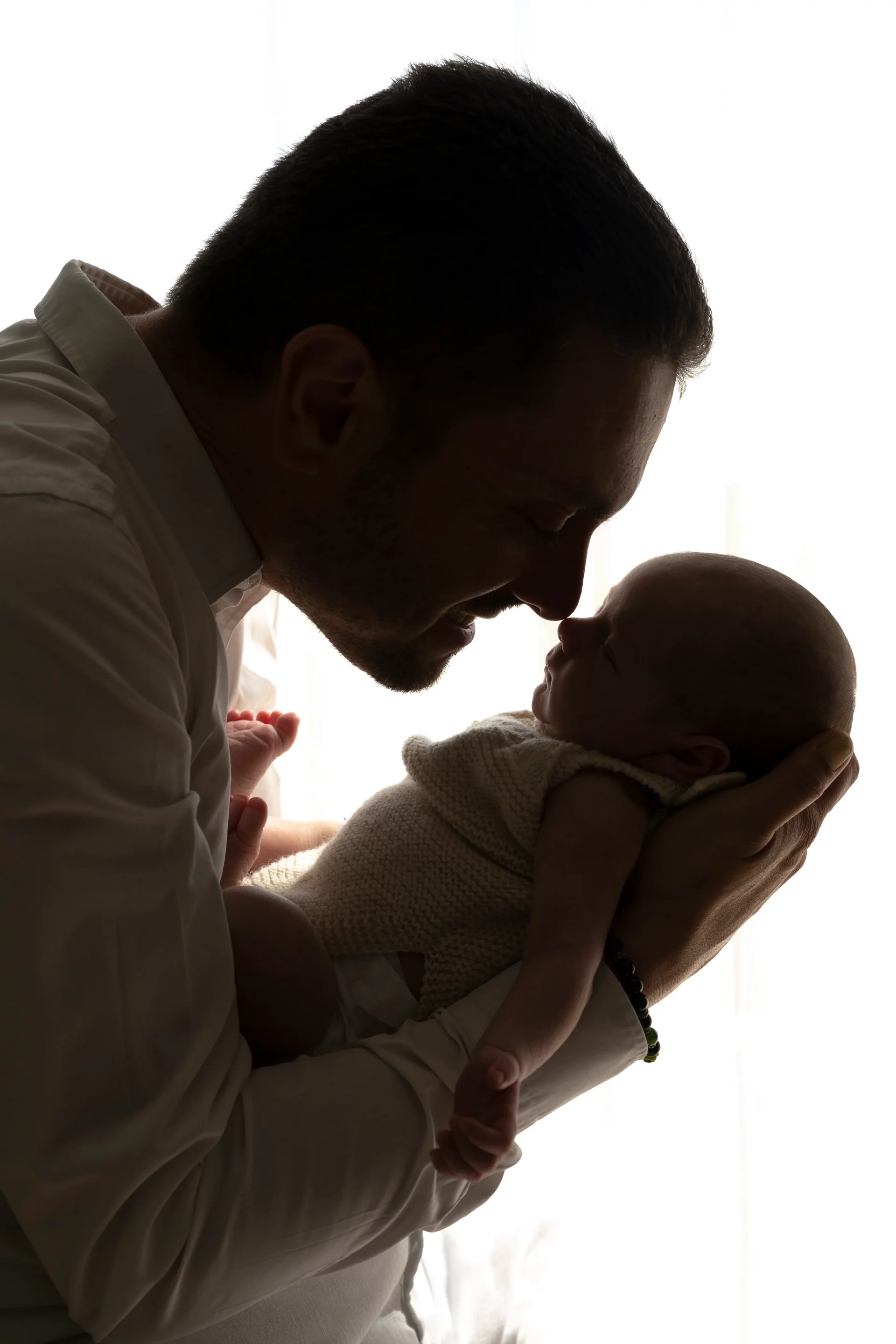 photo de naissance en ombre chinoise d'un père faisant un bisou esquimau à son bébé