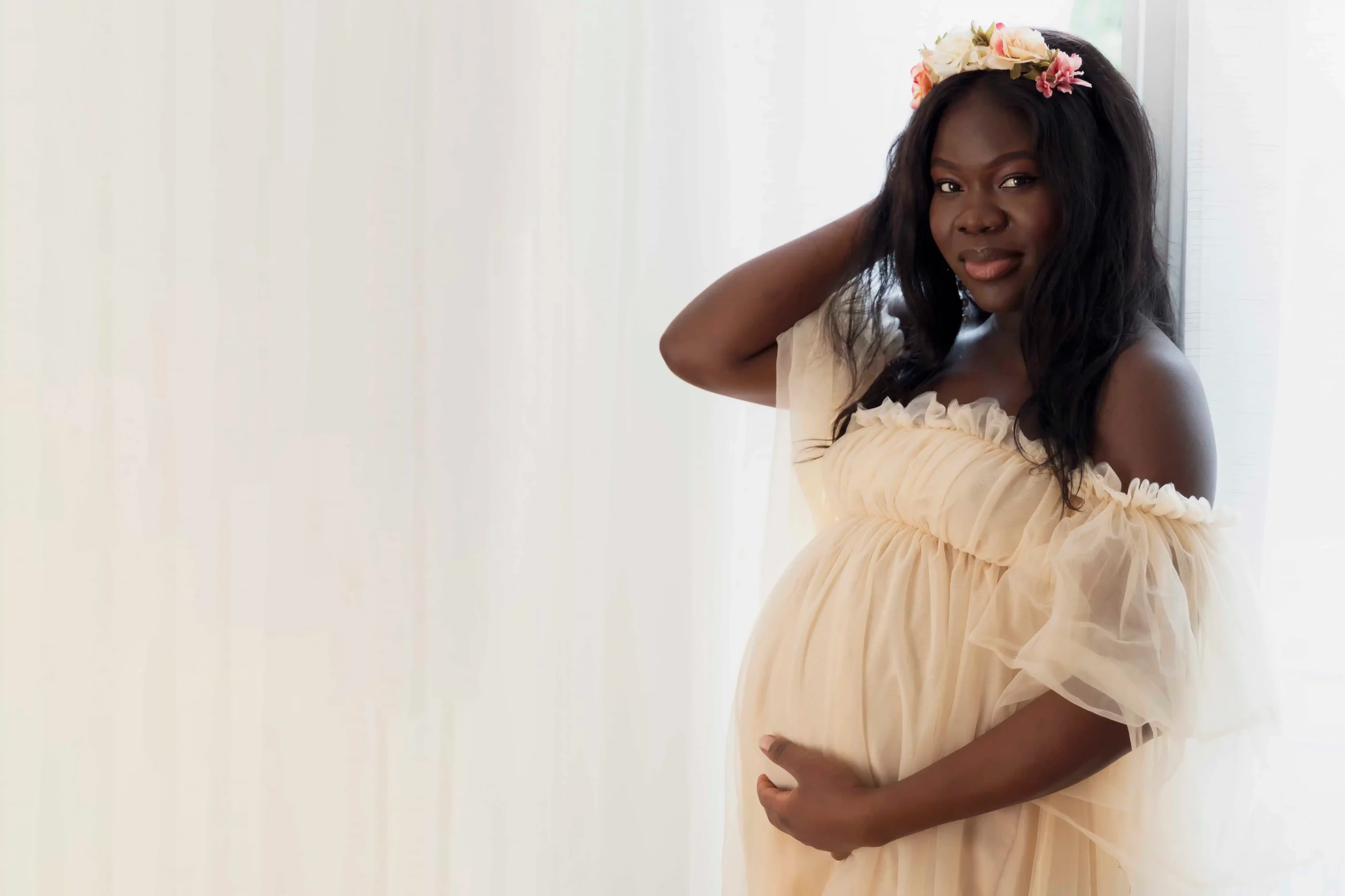 photo de grossesse d'une femme habillée en robe en voile rose