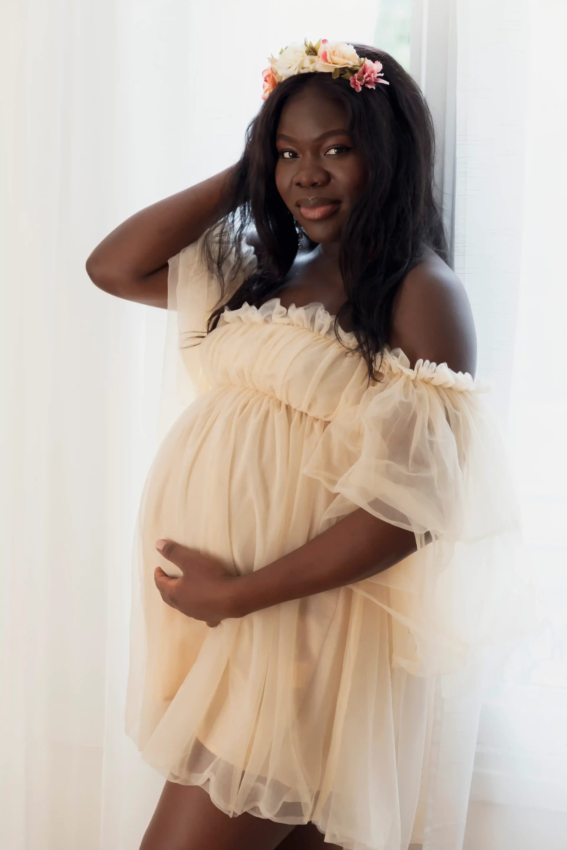 photo de grossesse d'une femme habillée en robe mousseline avec une couronne de fleur