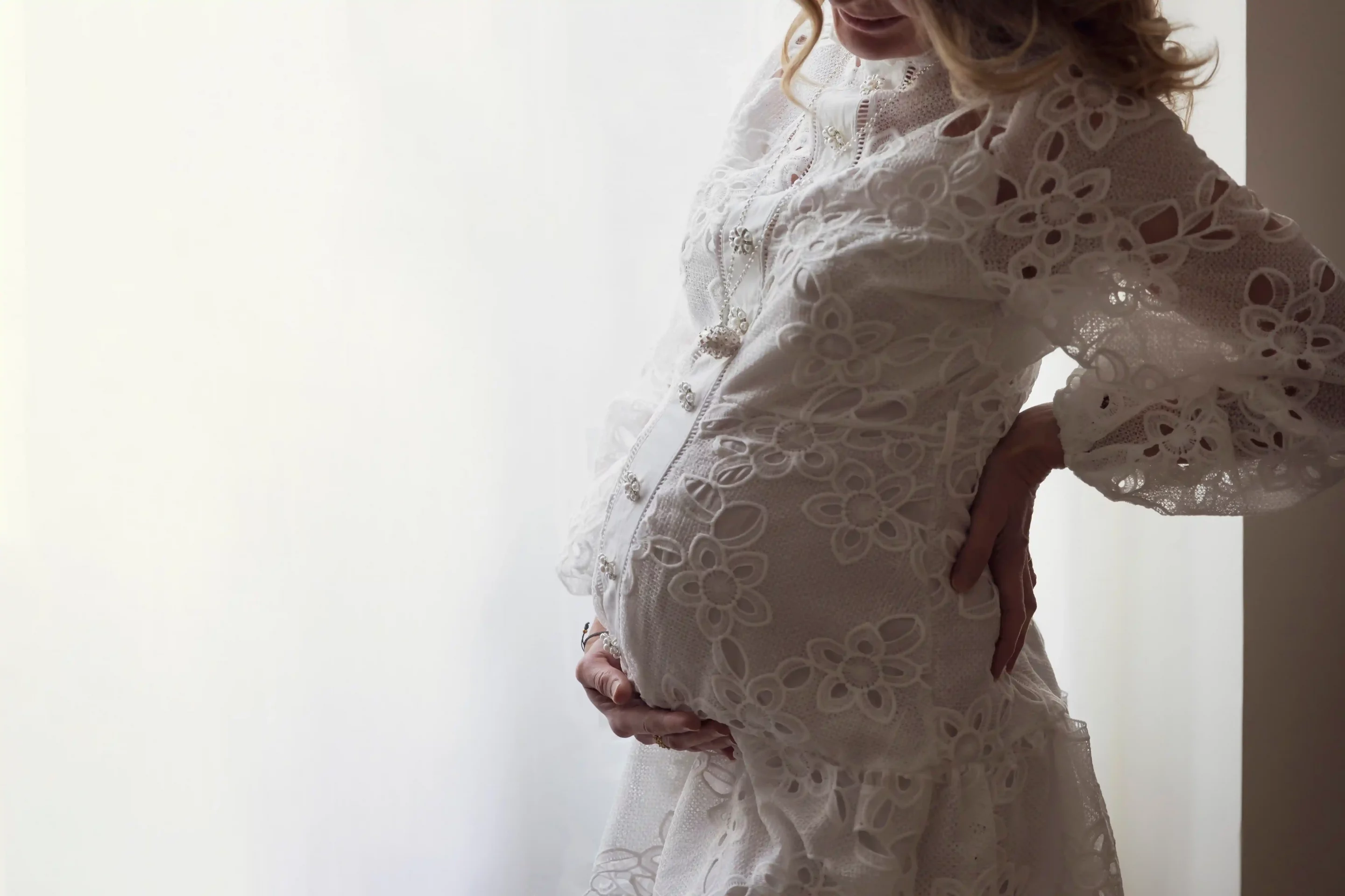 grossesse-shooting-photo-nice-studio photo de grossesse d'une maman habillée en robe blanche tenant son ventre