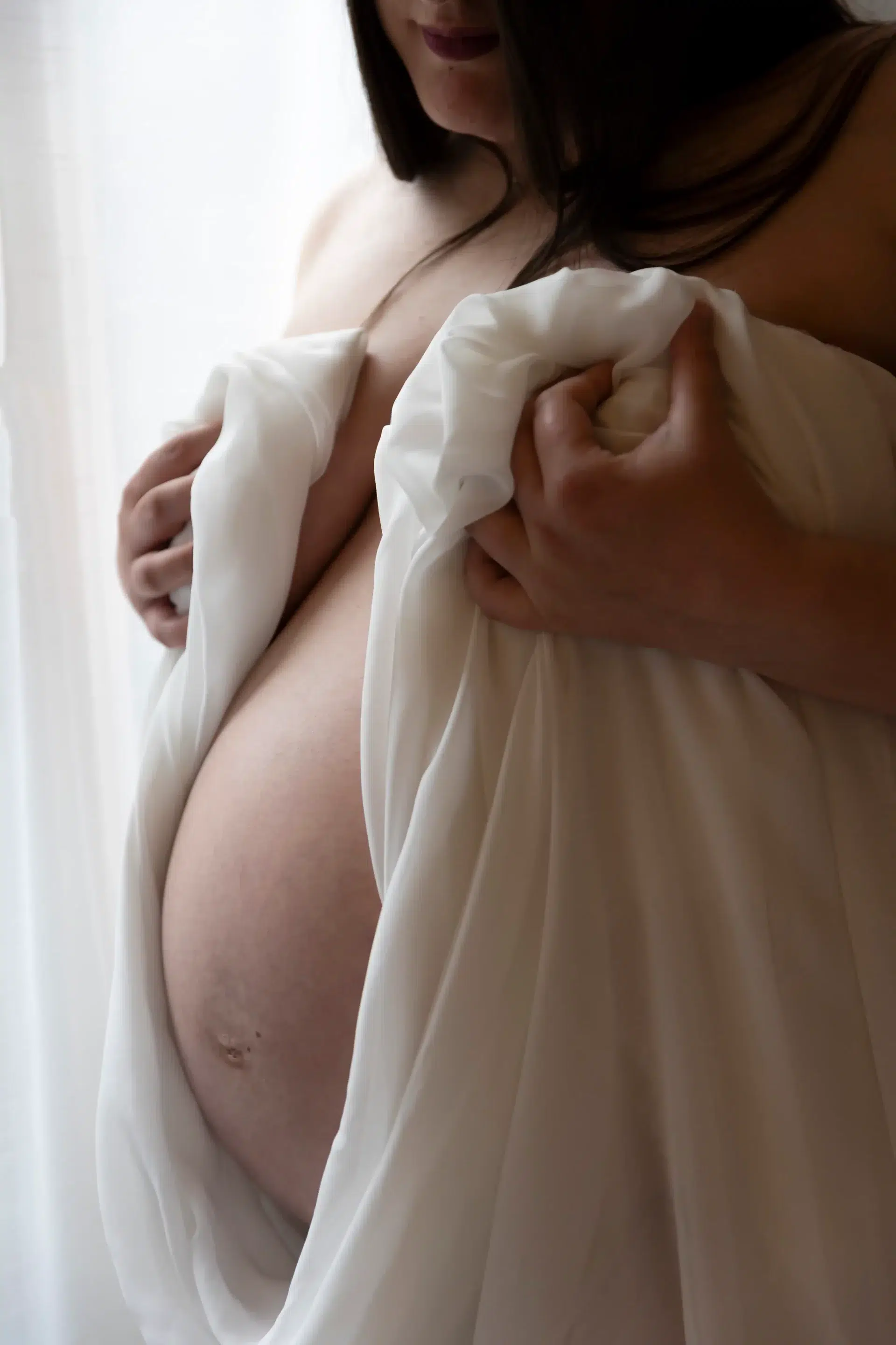 photo-de-grossesse-Nice-studio photo de grossesse d'une femme qui tient un voilage blanc, entourant son ventre