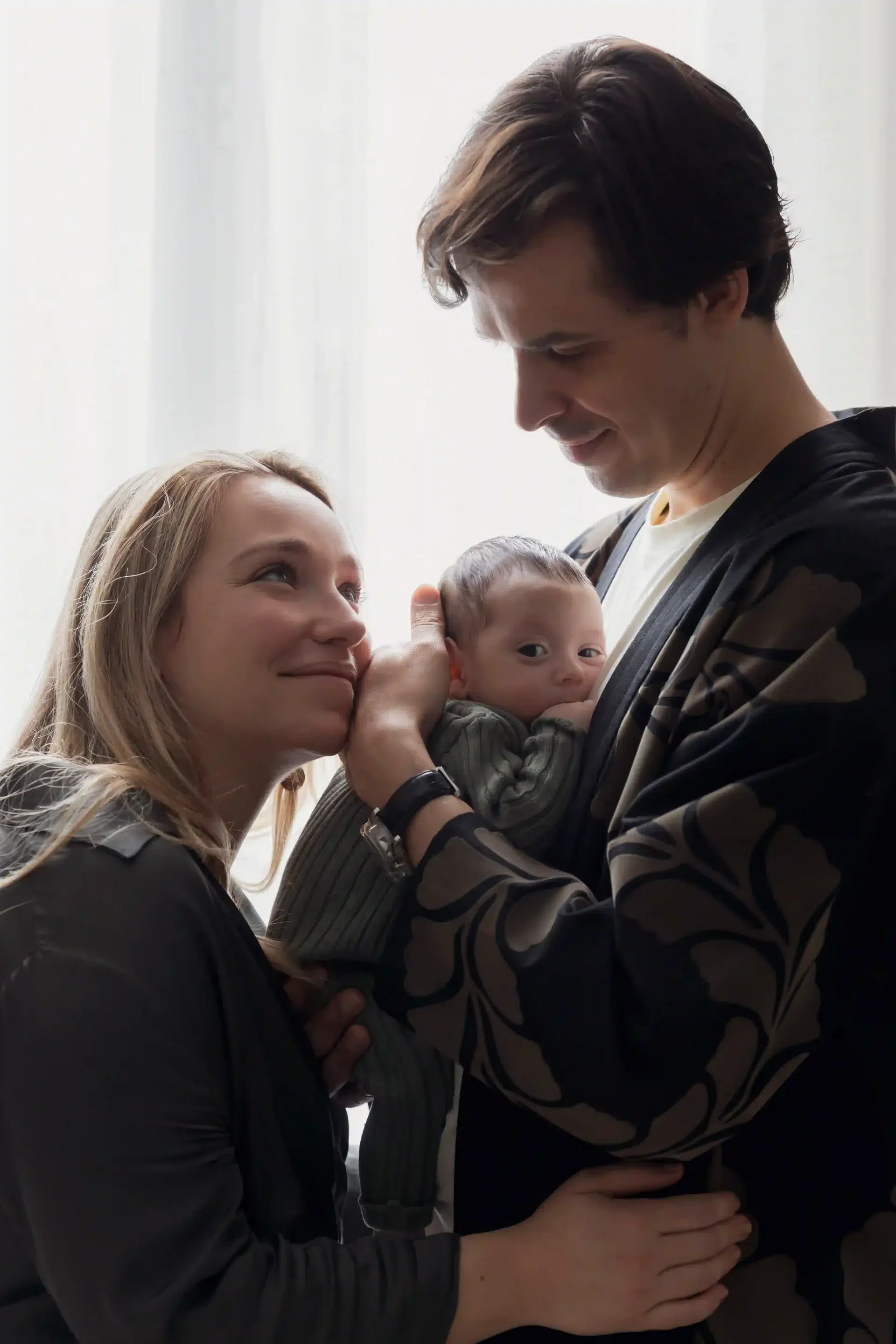 photo de naissance d'un couple se regardant en tenant leur bébé