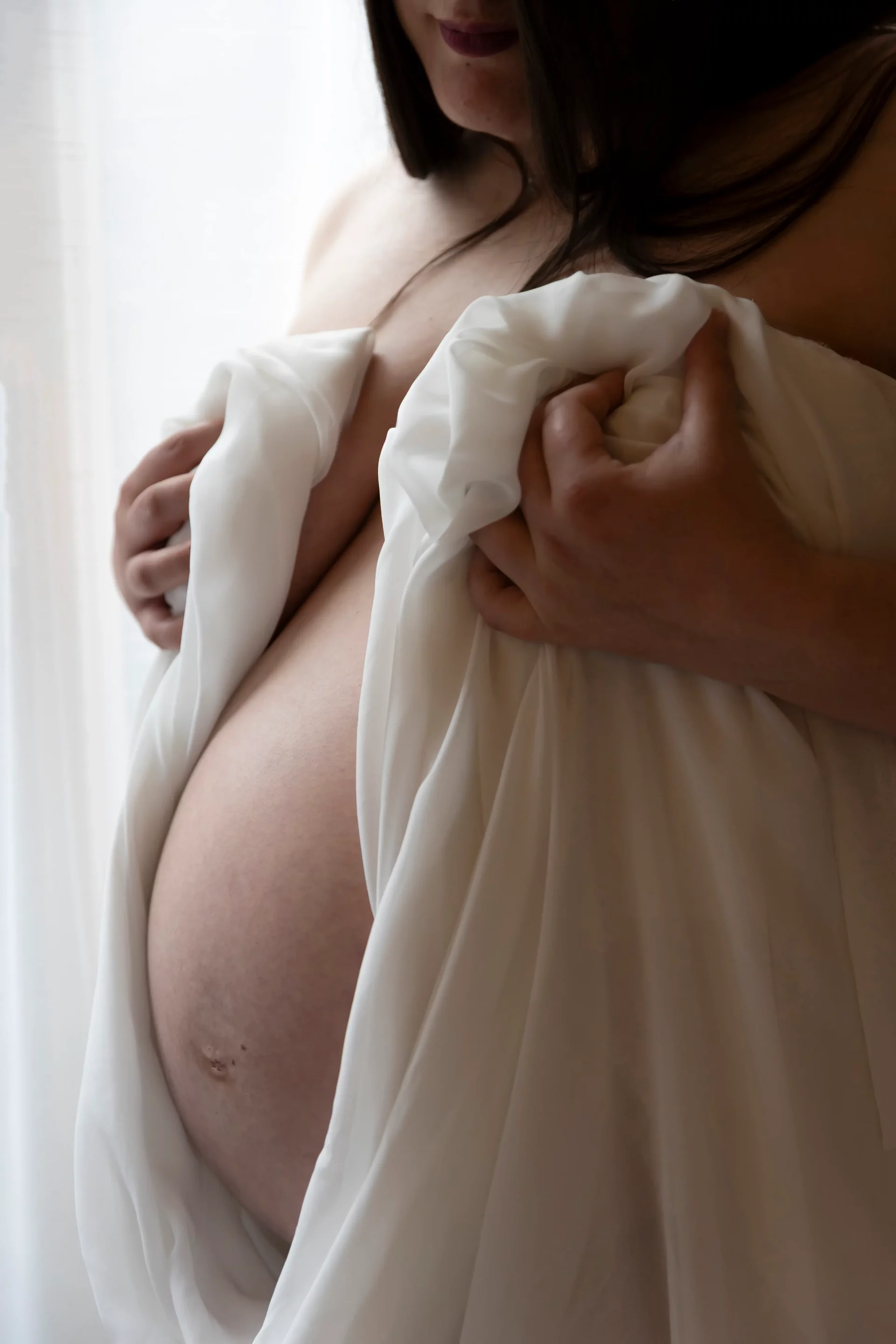 photo de grossesse, gros plan dur le ventre d'une femme entouré d'un voile blanc