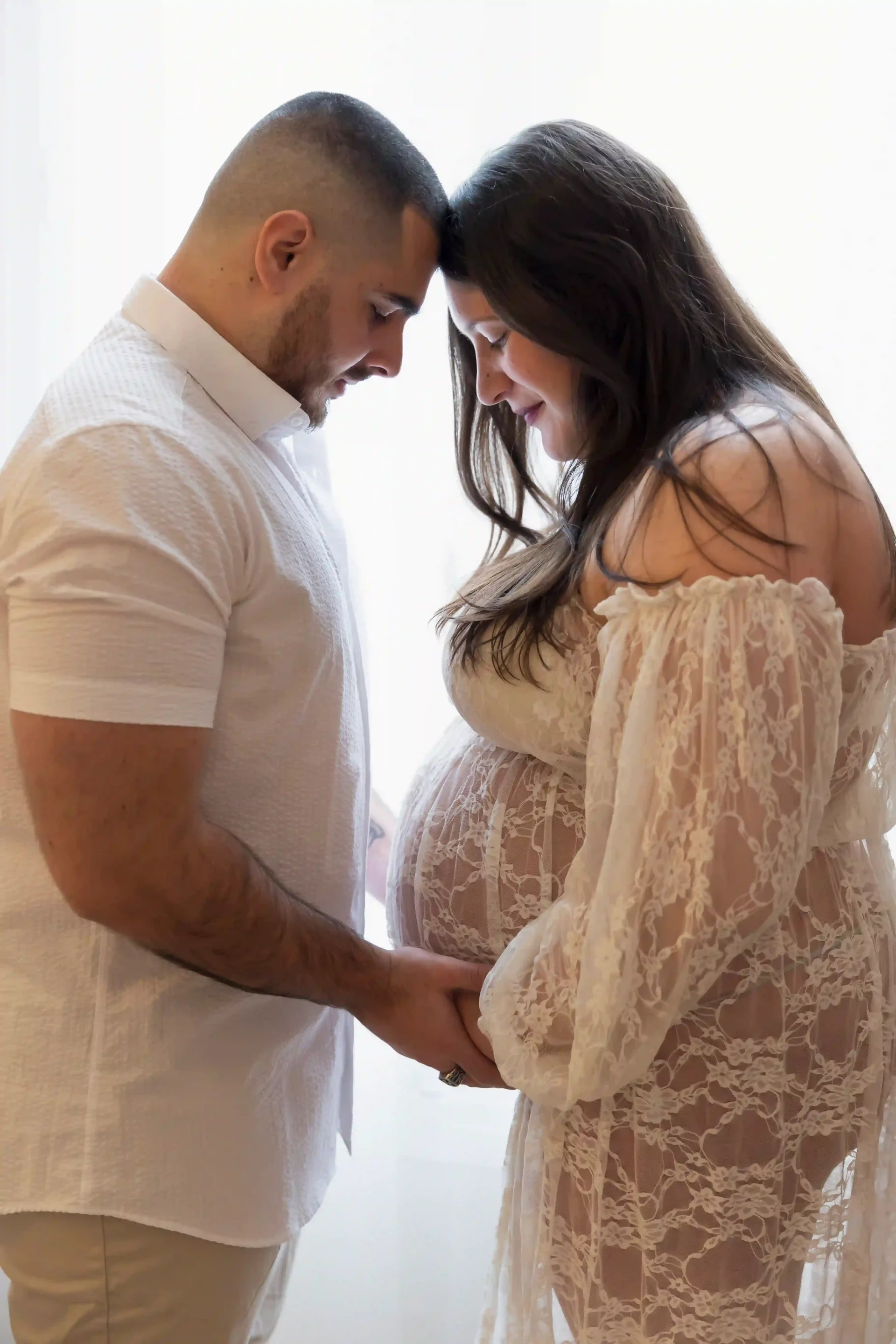 phot de grossesse d'un couple qui regardent le ventre front contre front