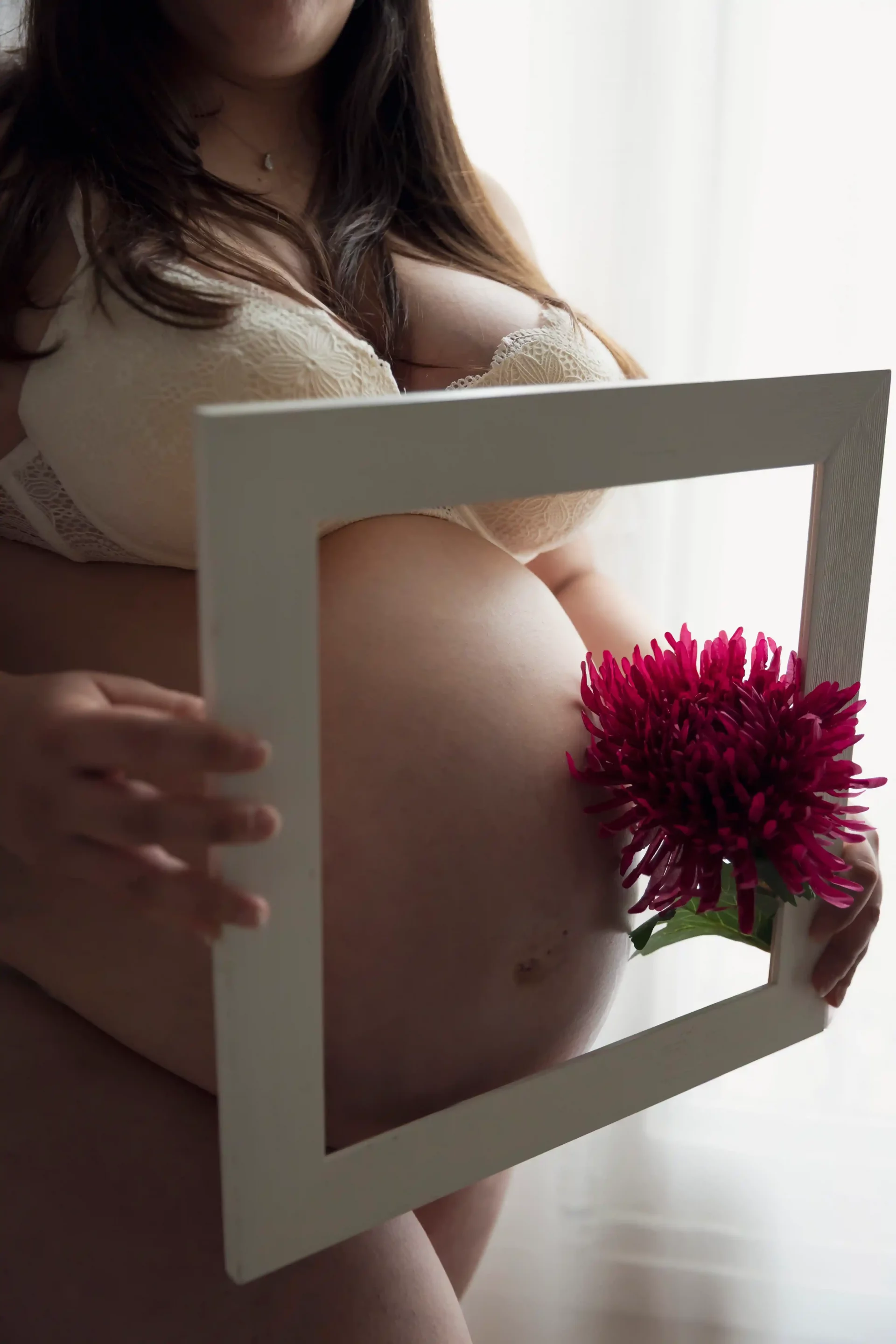 photo de grossesse, d'un ventre mis en valeur par un cadre et une fleur rouge