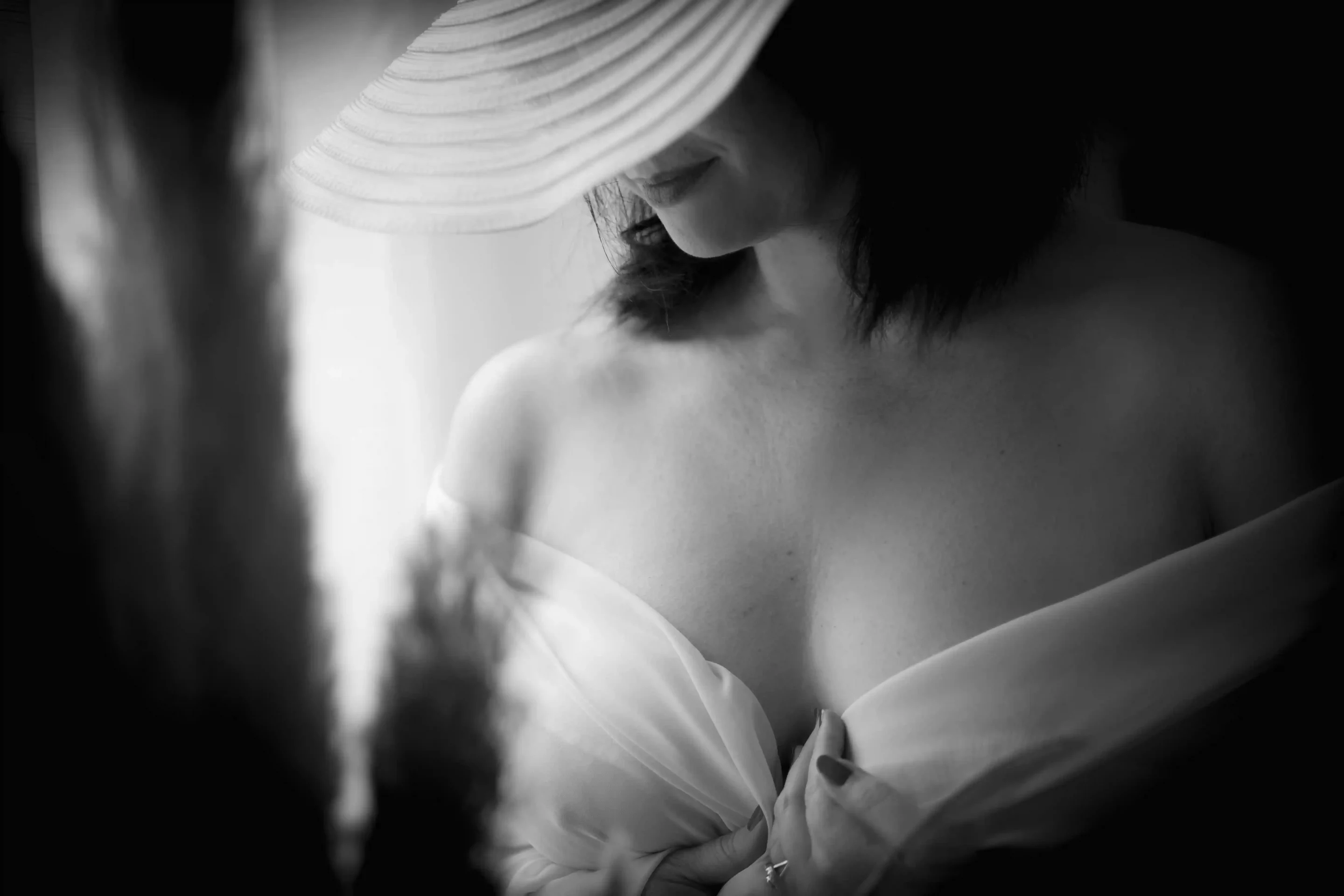 photo de boudoir d'une femme portant un chapeau blanc et un voile blanc sur sa poitrine