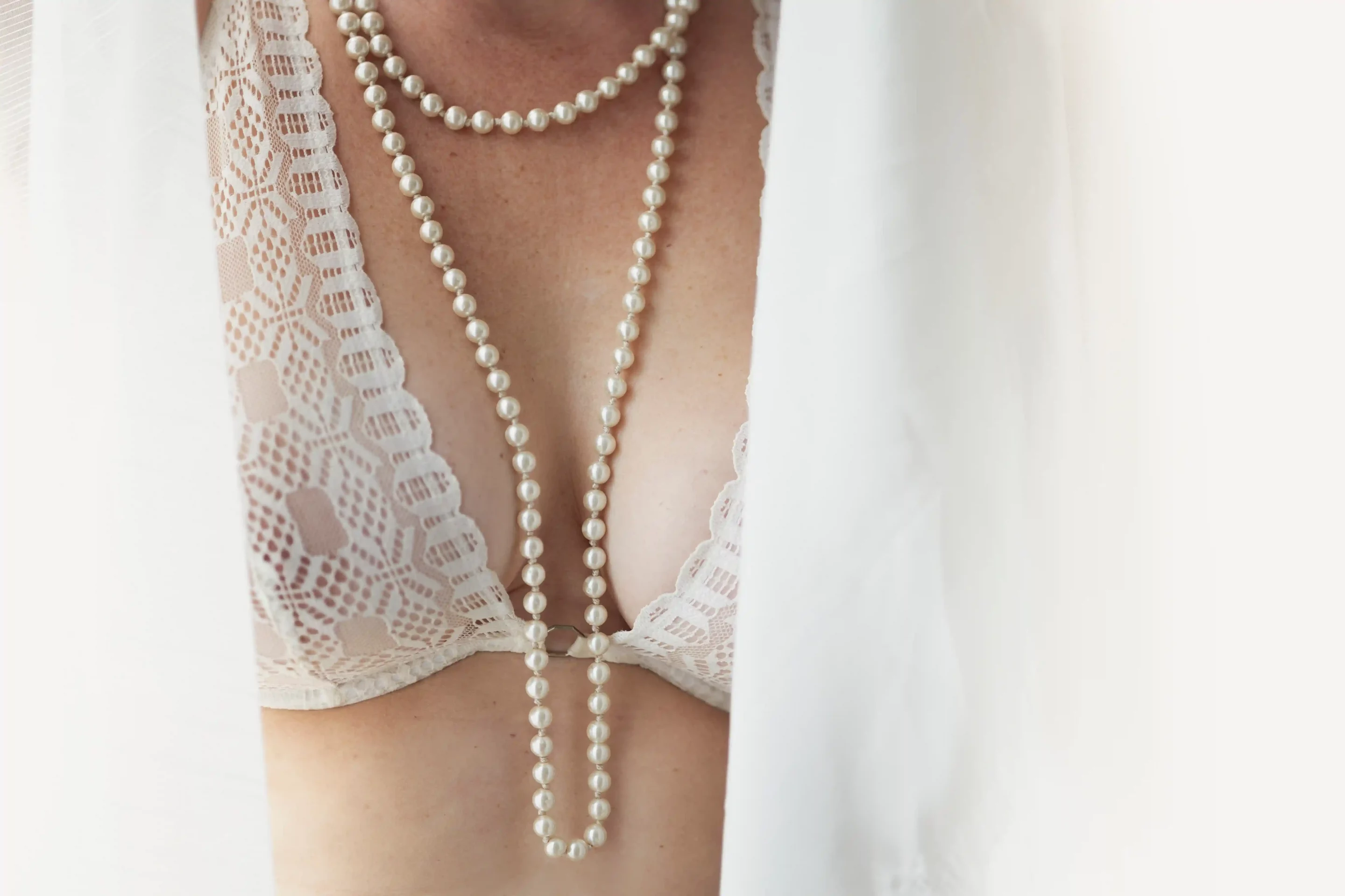 photo boudoir, une poitrine cachée entre deux voilages blancs