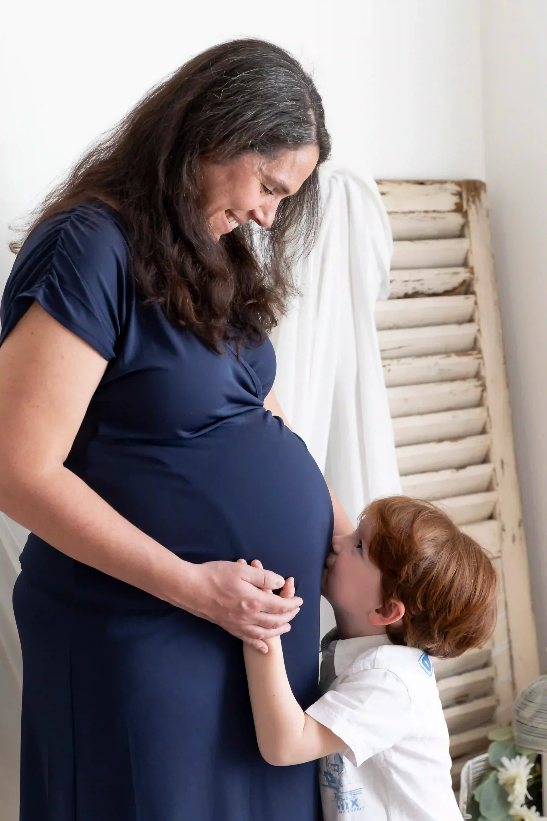 photo de grossesse d'un petit garçon embrassant le ventre de sa maman