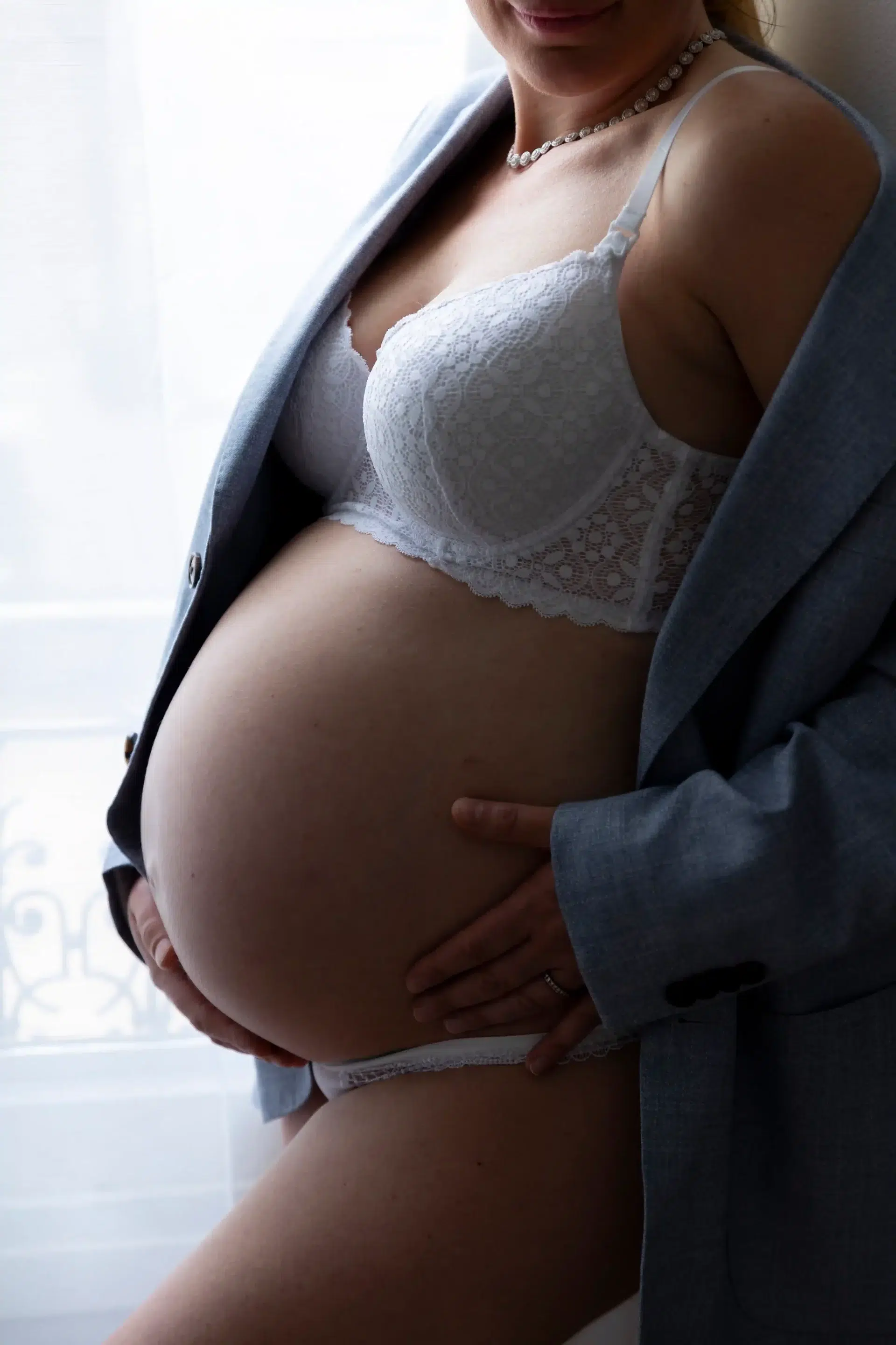 photo de grossesse, gros plan sur le ventre de la maman, vêtue d'une veste bleue