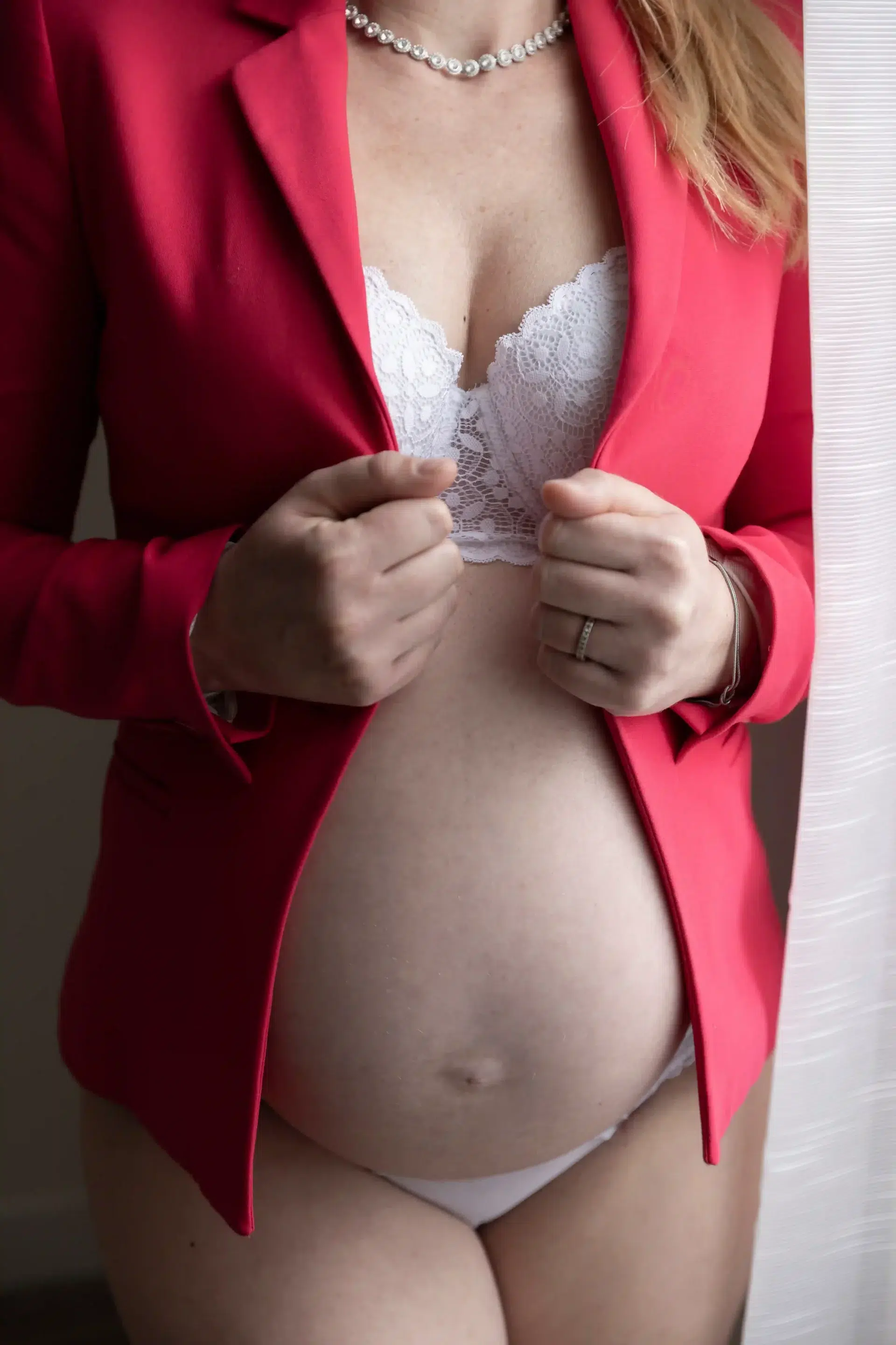 photo de grossesse, gros plan sur le ventre de la maman, vêtue d'une veste rose