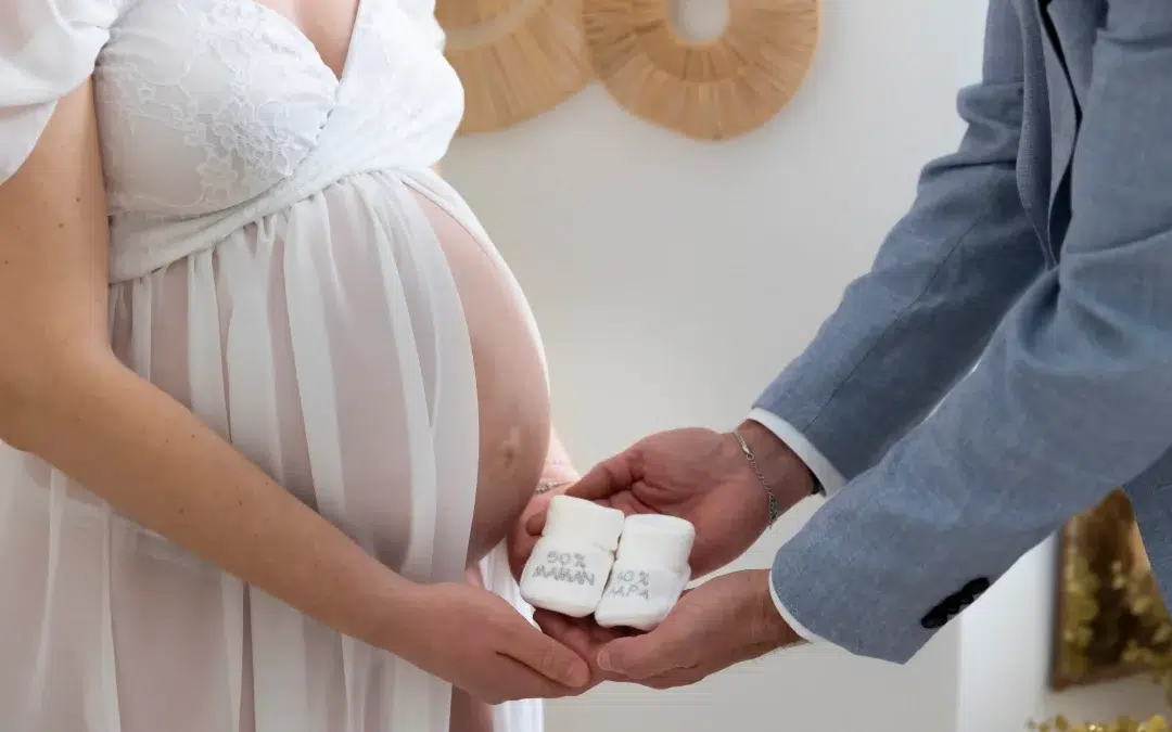 photo de grossesse, d'un couple tenant dans leurs mains des petits chaussons
