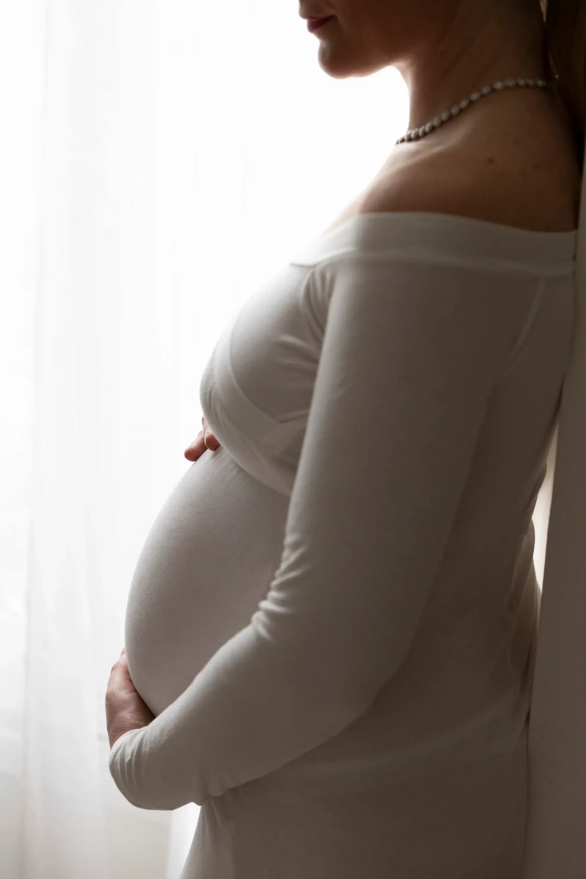 photo de grossesse, une femme tenant son ventre en robe blanche