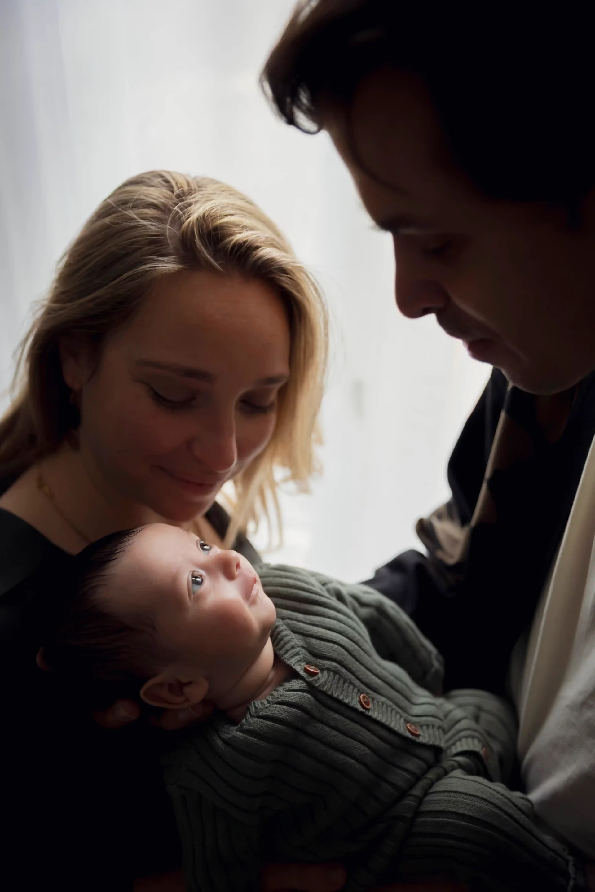 photo de naissance d'un couple admirant son bébé. Le bébé sourit au papa