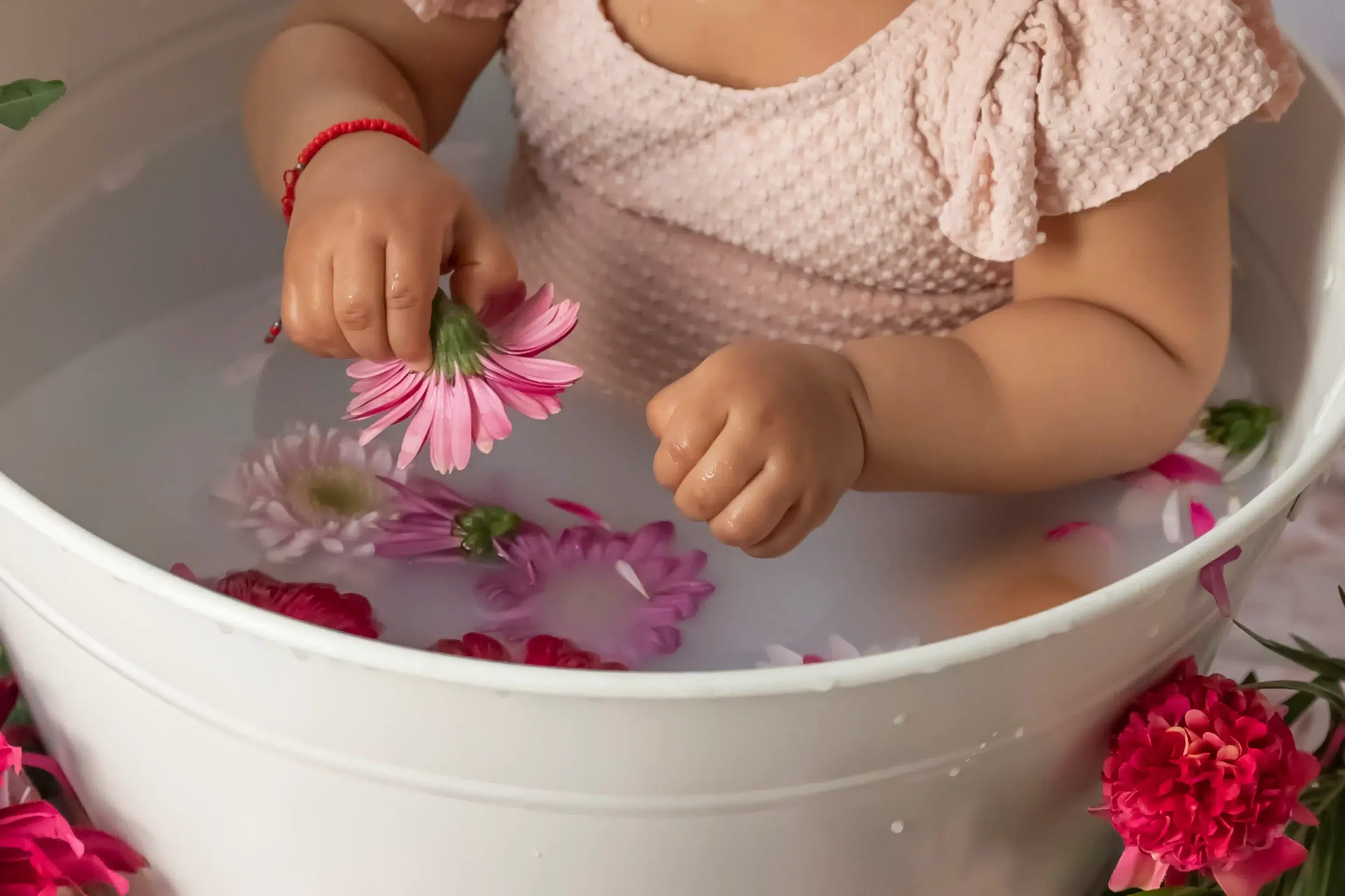 photo bain de lait, gros plan sur la main d'un bébé tenant une fleur