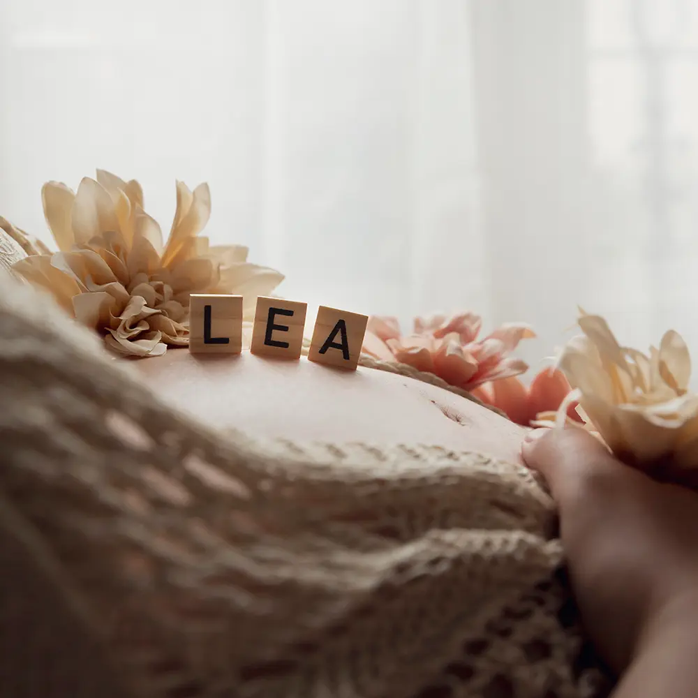 photo de grossesse, gros plan sur le ventre de la maman et le prénom du bébé écrit en lettre de scrable