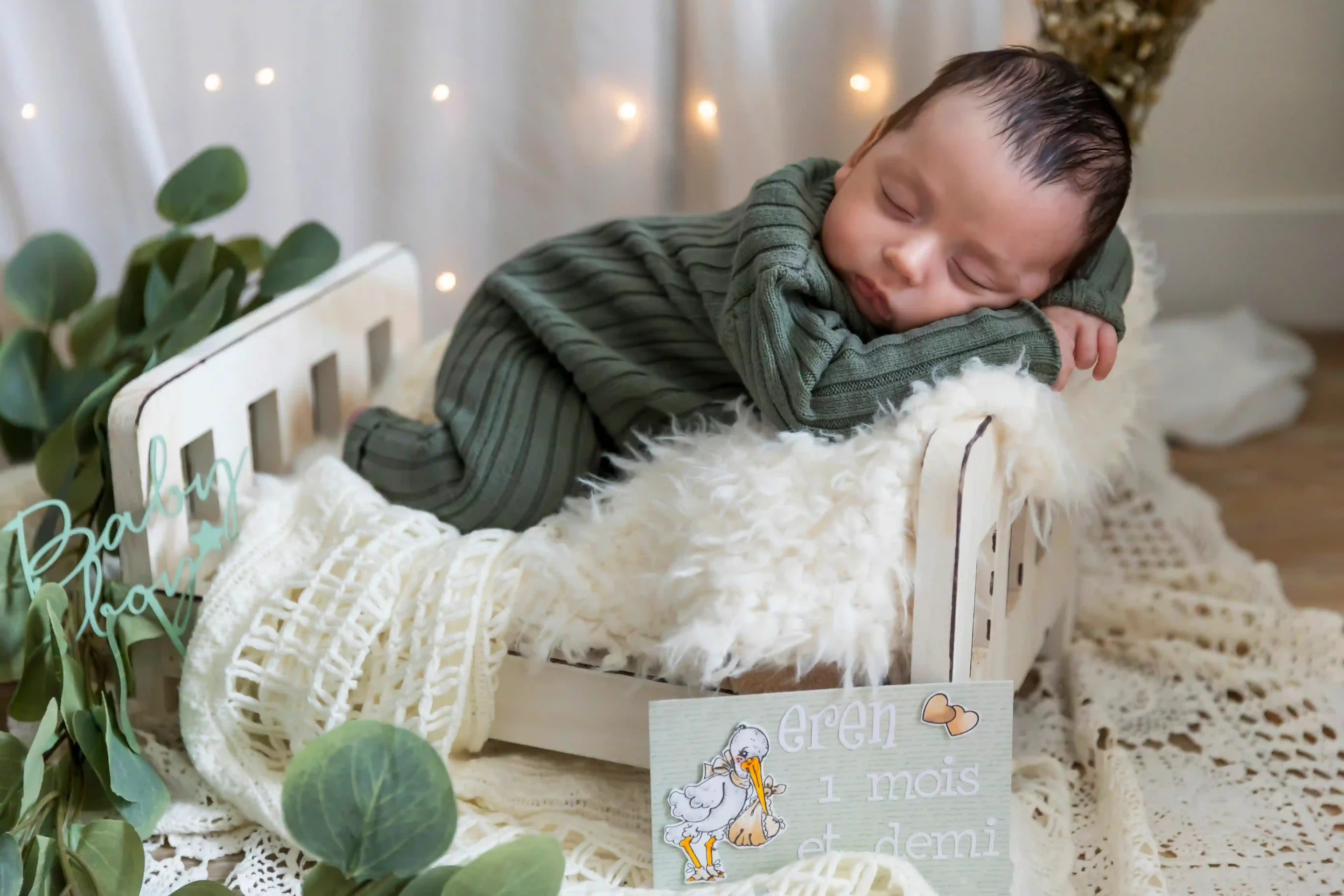 photo de naissance,d'un bébé endormi sur le dos dans un petit lit blanc