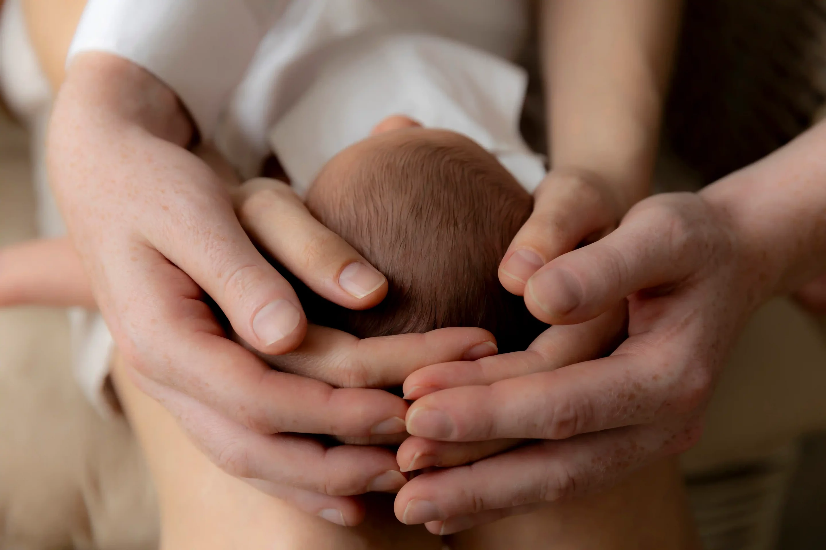 photo de naissance, gros plan sur les cheveux du bébé et les mains des parents