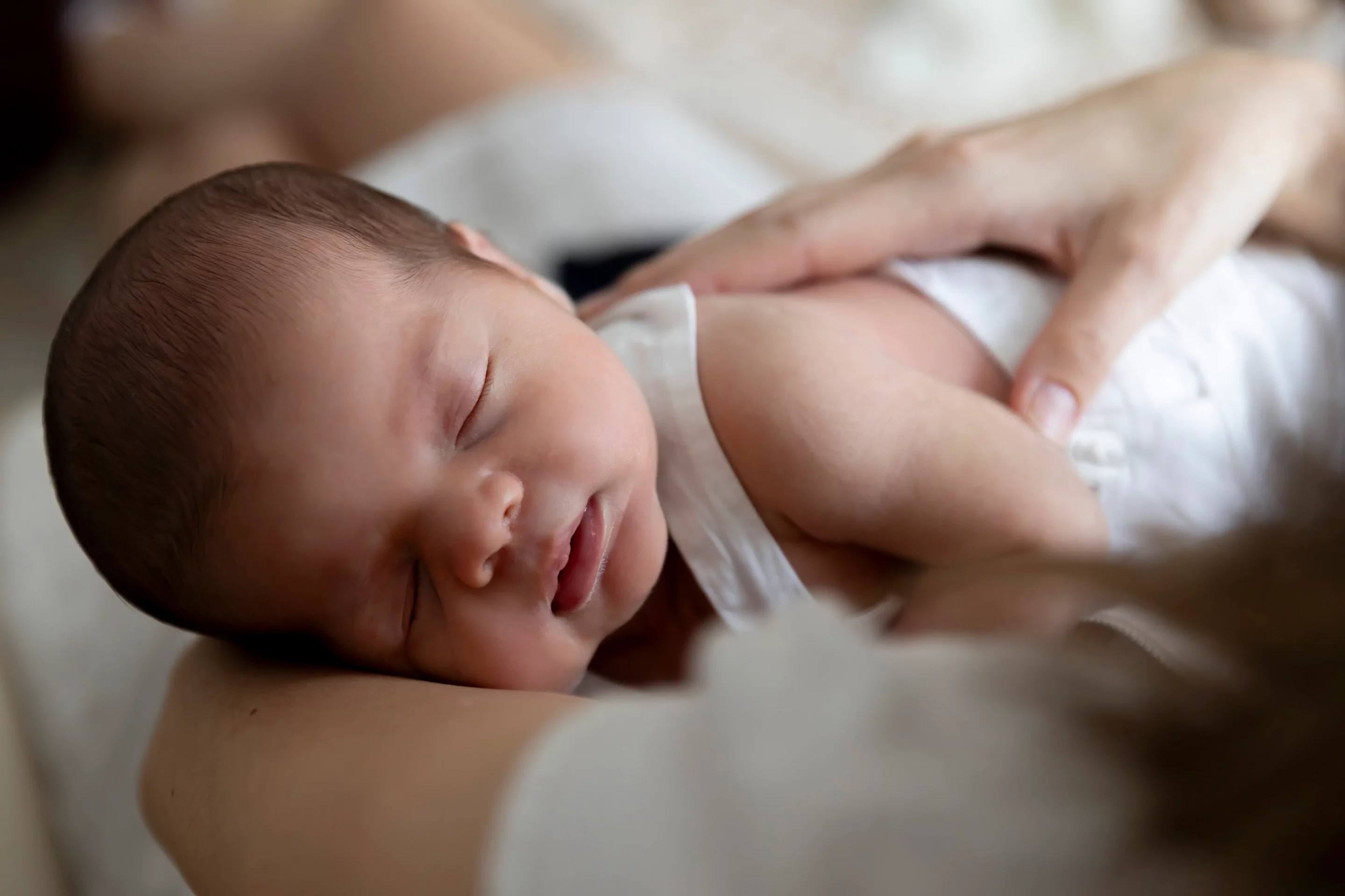 photo de naissance, d'un bébé endormi paisiblement dans les bras de sa maman