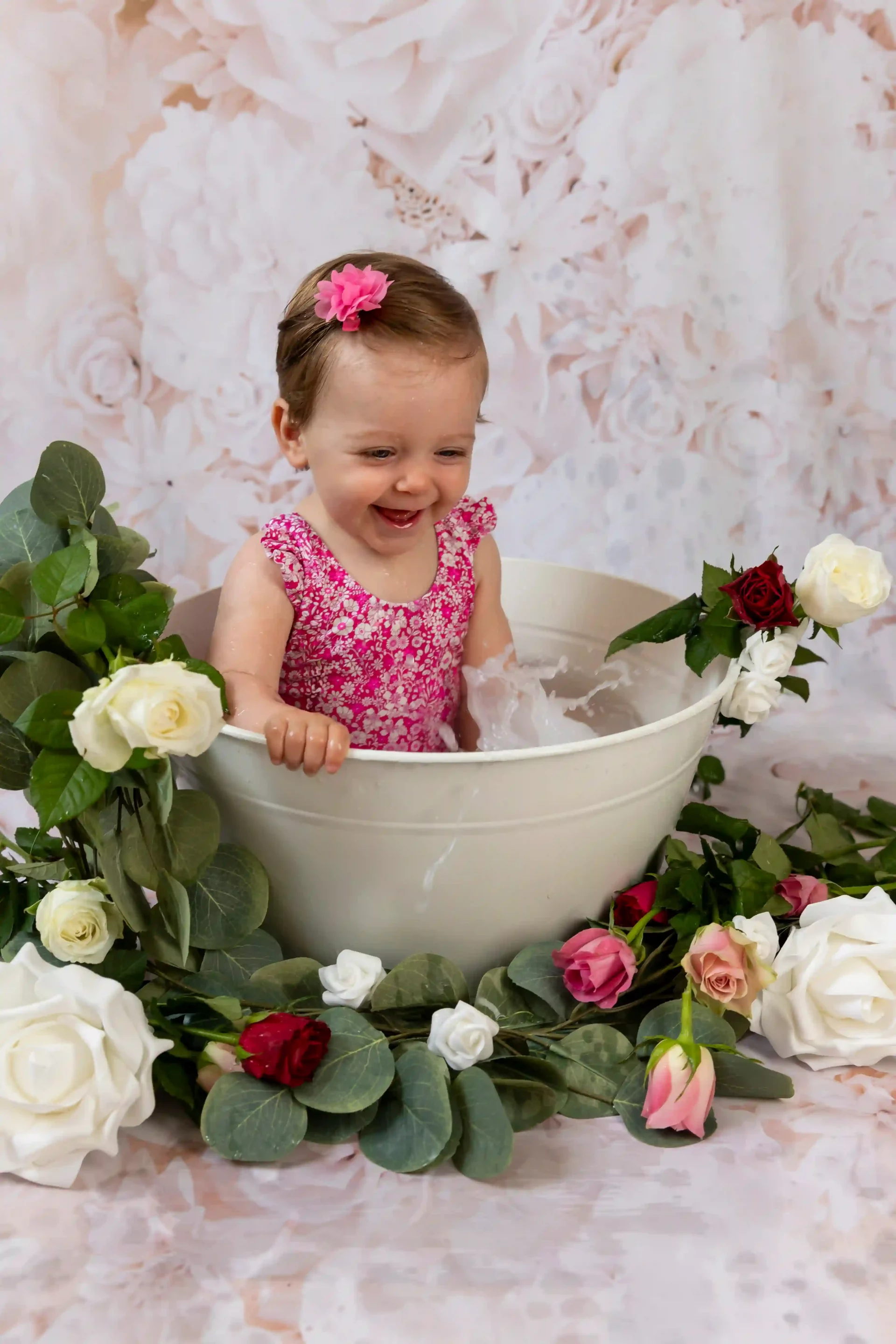 photo bain de lait d'une petite fille en maillot rose, eclaboussant son bain