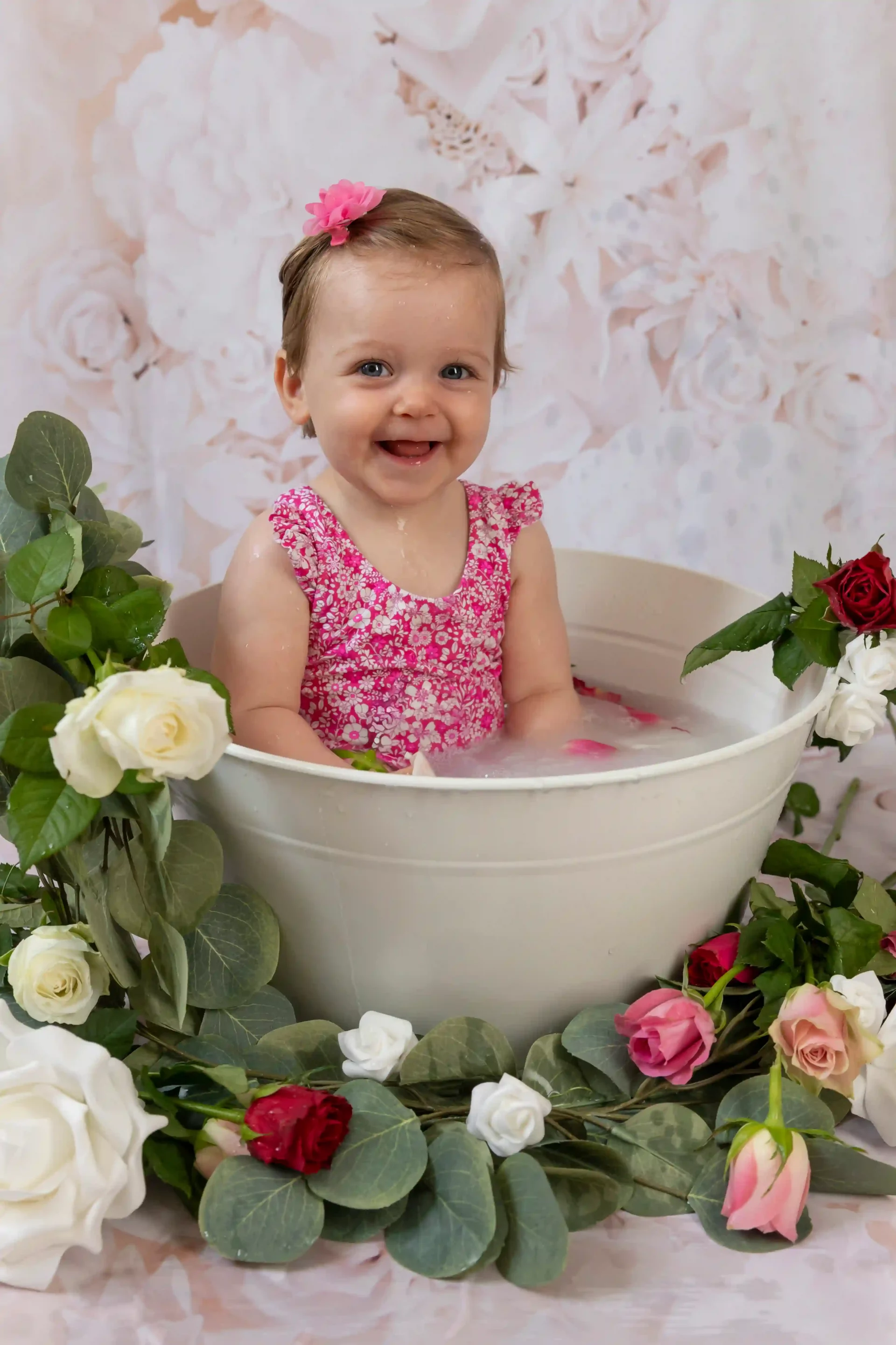 photo bain de lait d'une petite fille en maillot rose entourée de fleurs roses