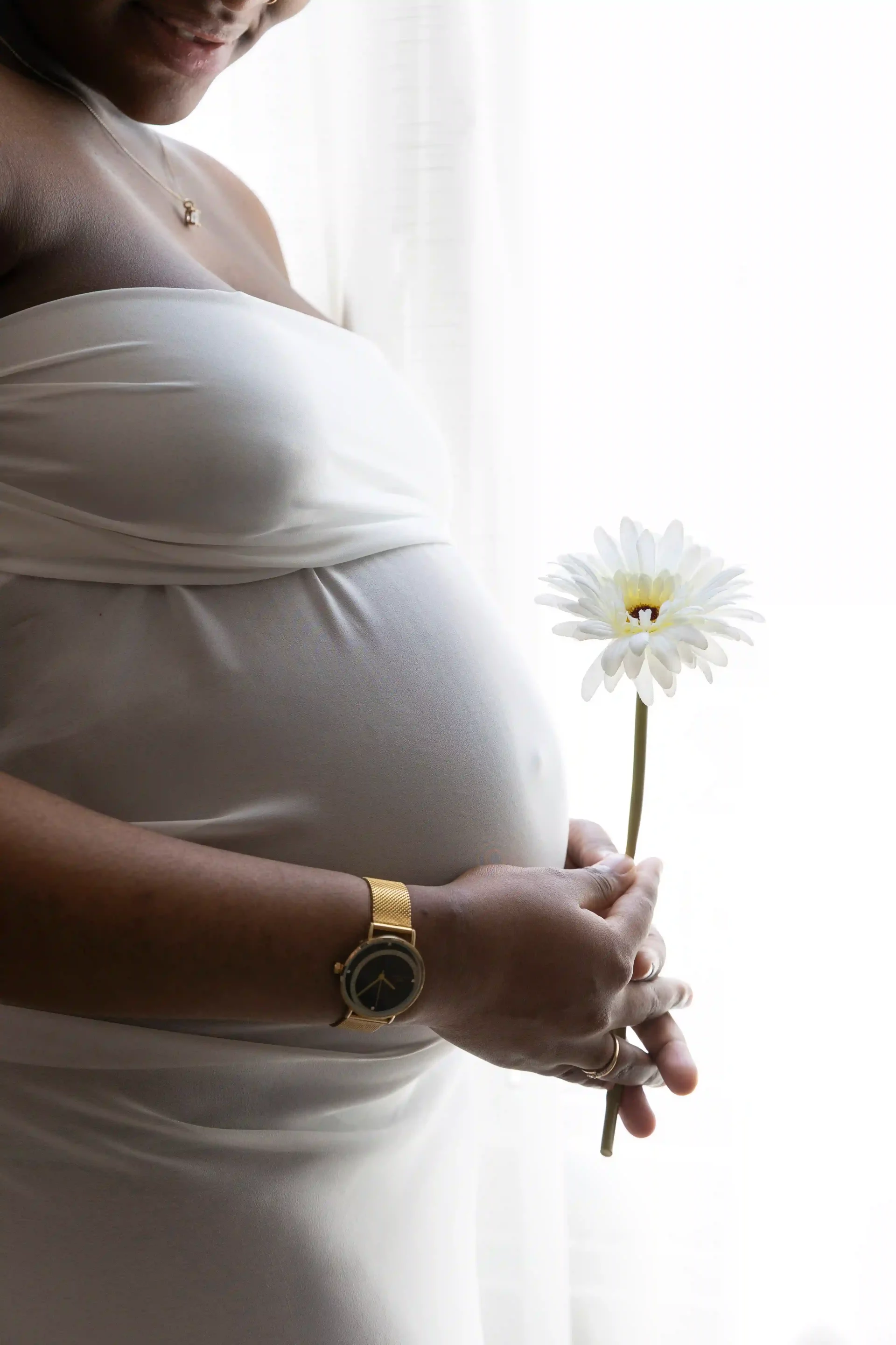 photo de grossesse, gros plan sur le ventre d'une femme, tenant un fleur blanche devant son ventre