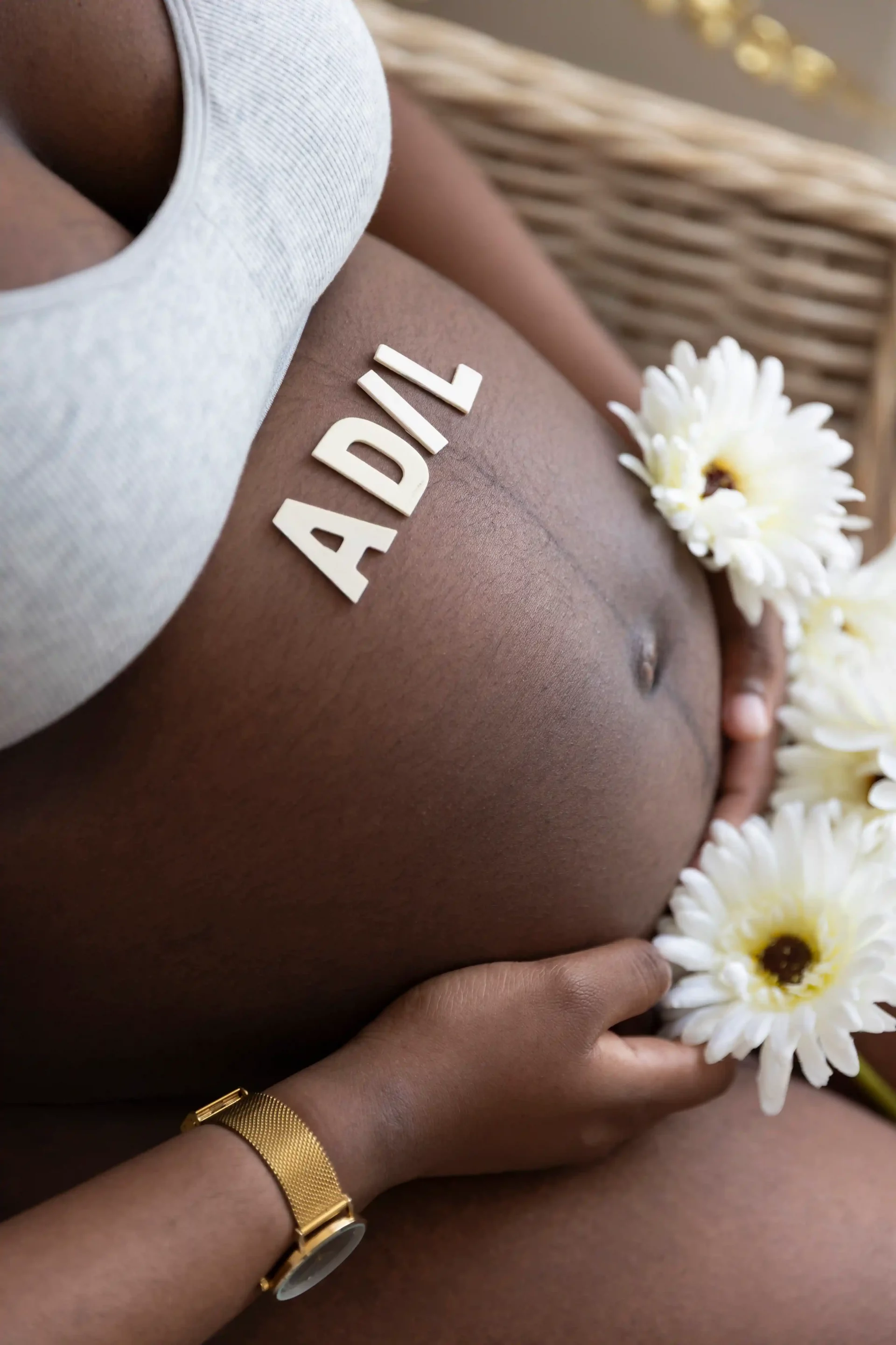 photo de grossesse, le prénom du bébé est écrit sur le ventre avec des lettre en bois