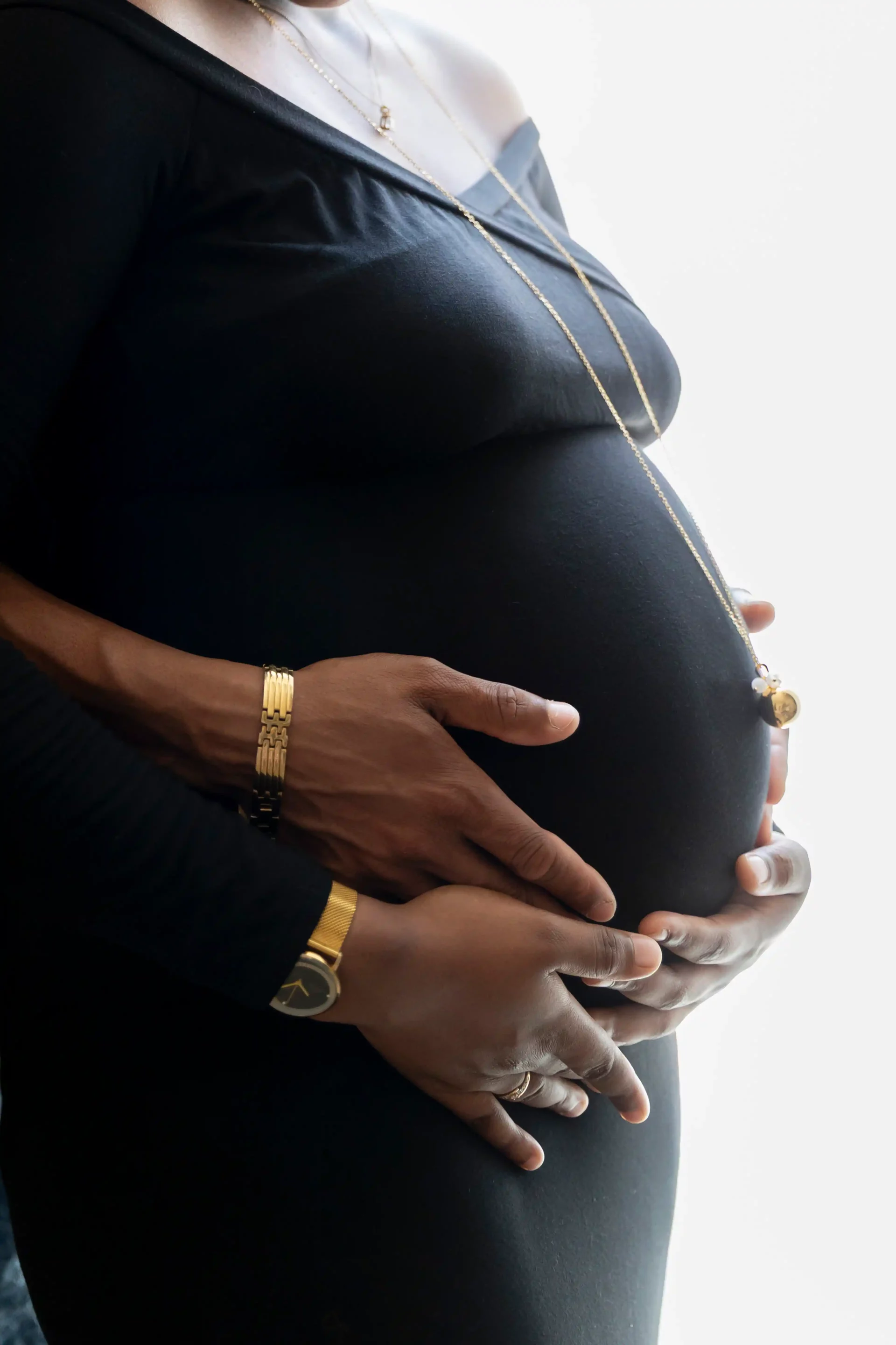 photo de grossesse, ,gros plan sur les deux mains des parents, posées sur le ventre