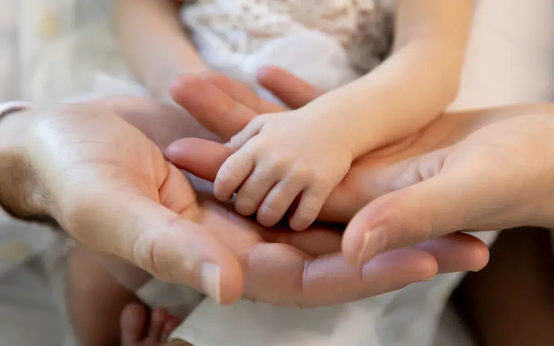 séance photo de naissance, gros plan sur les mains du bébé et des parents