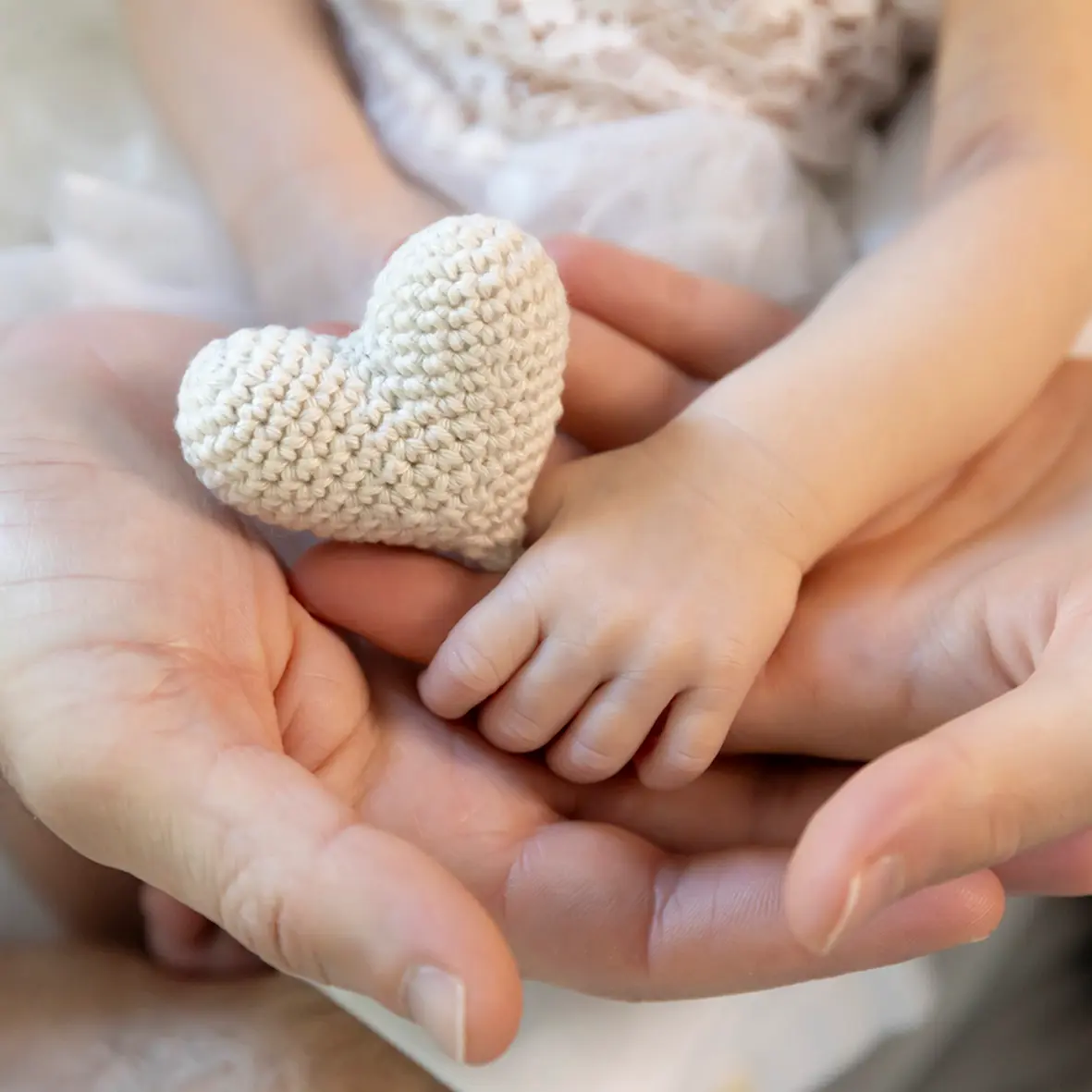 photo de naissance, gros plan sur les 3 mains des parents et bébé